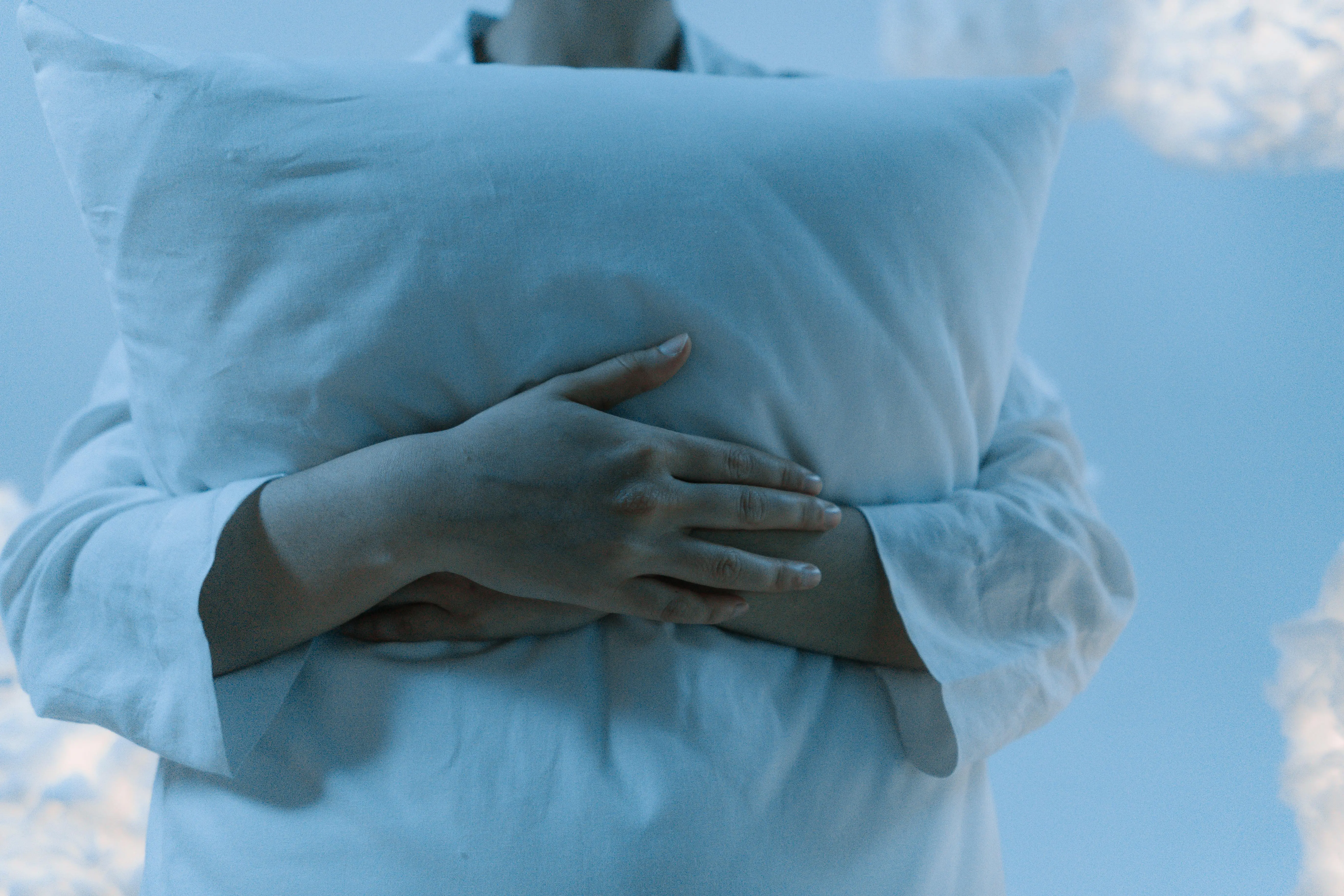 blue and white pillows A serene scene depicting a person gently hugging a pillow, showcasing calmness and comfort.