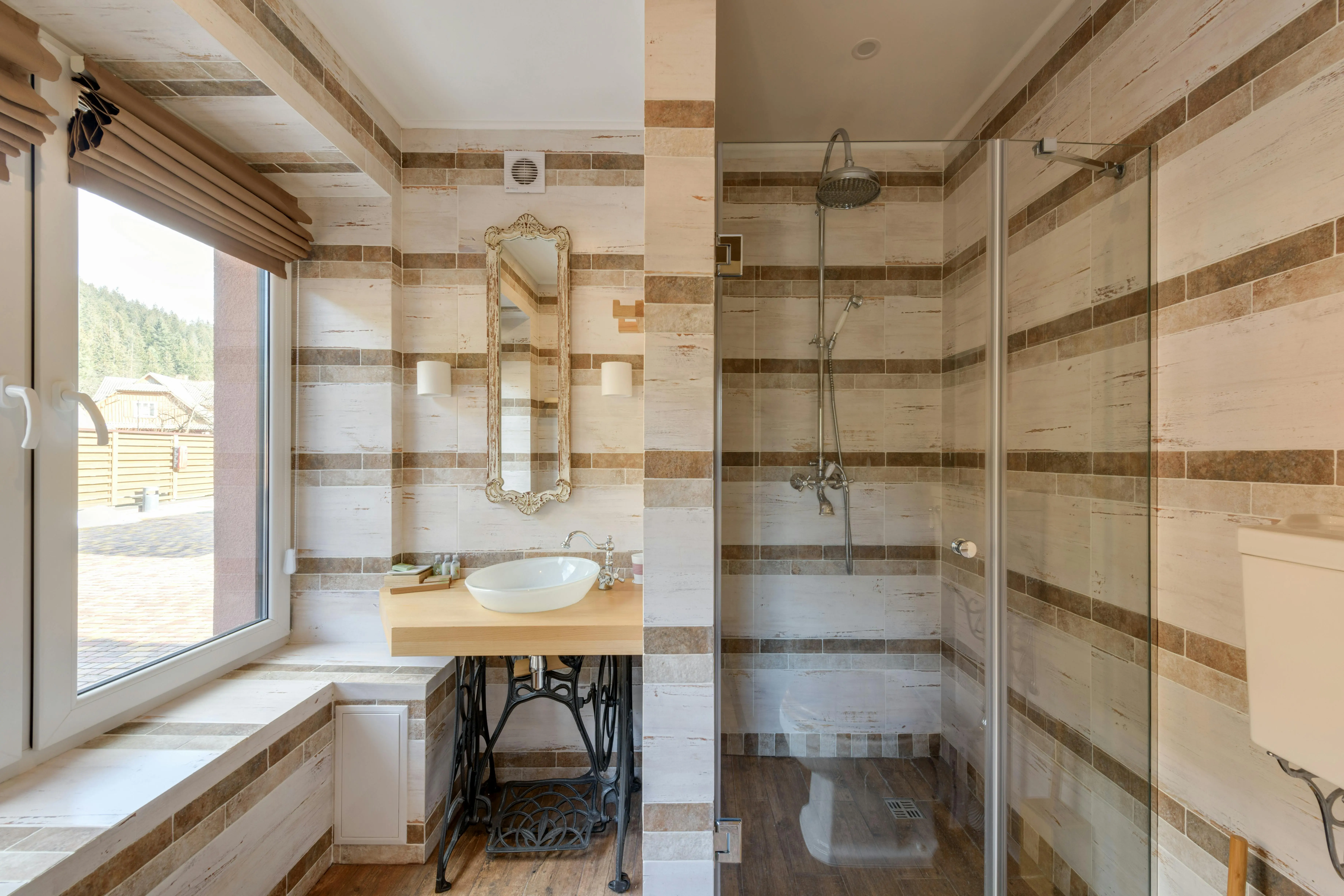 brown tiles A stylish bathroom featuring a rustic vanity and a glass shower with natural light.