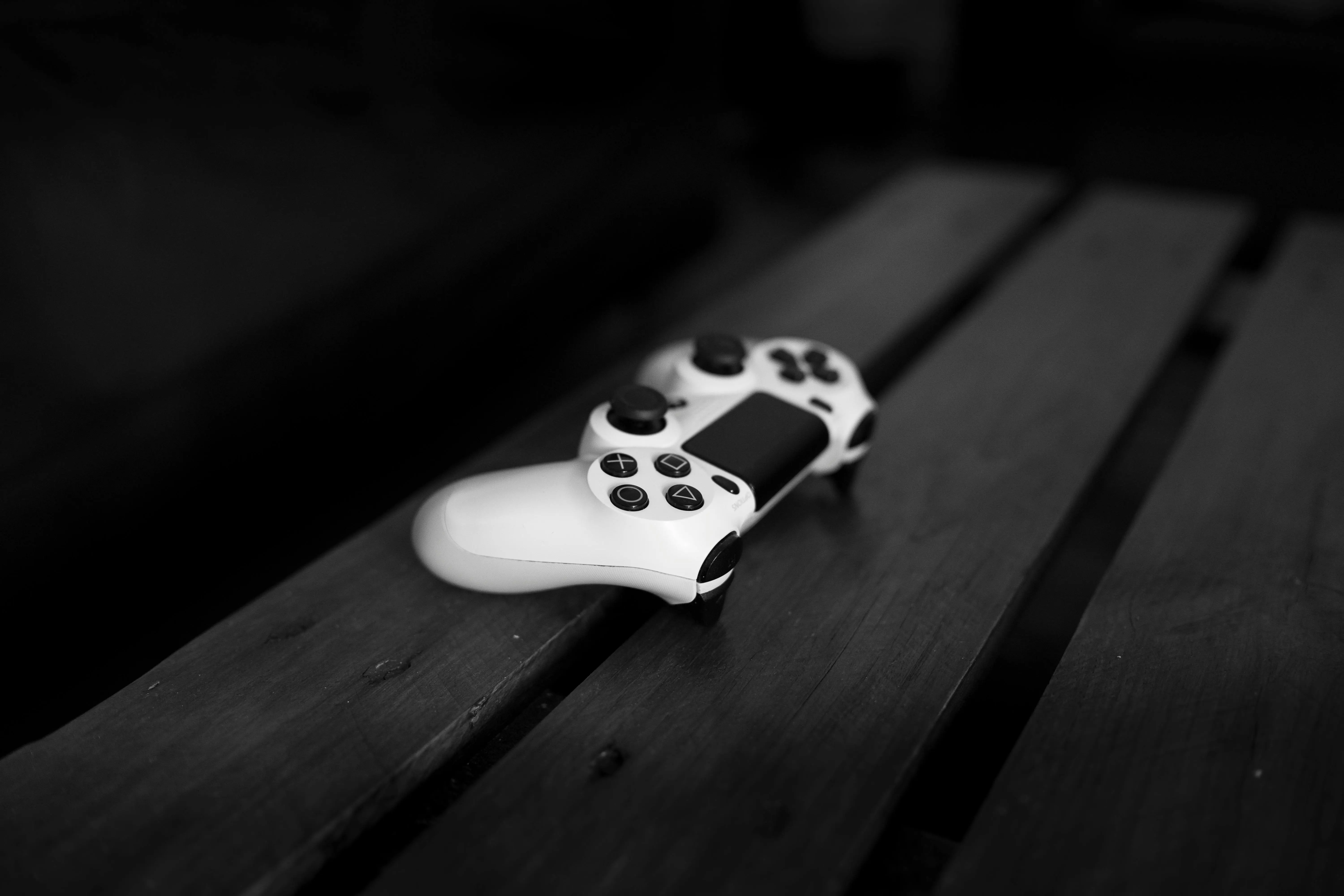 extendable console table Black and white photo of a gaming controller on a wooden table, perfect for gaming or tech themes.