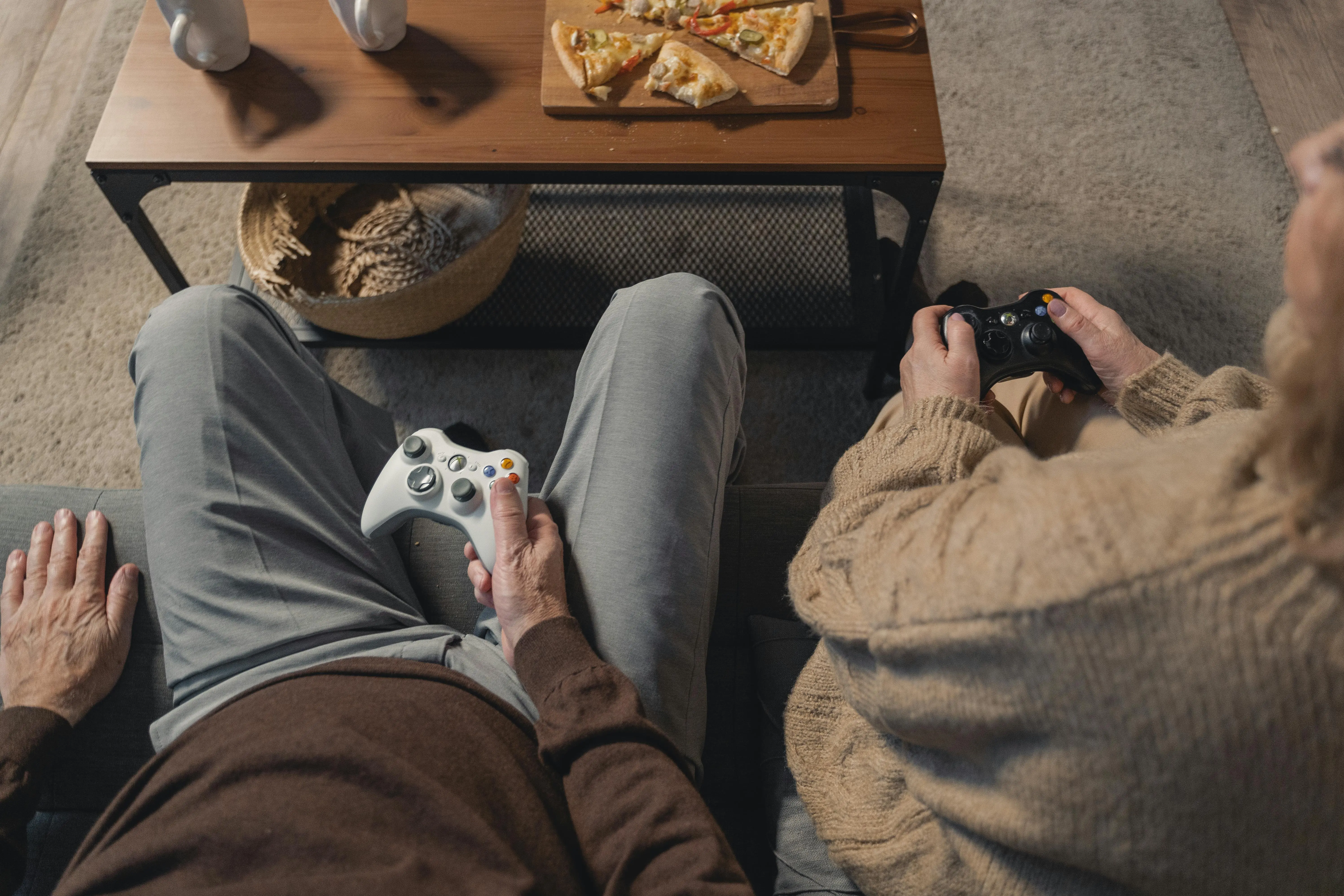 extendable console table Elderly couple playing video games on the sofa, enjoying leisure time with a console.