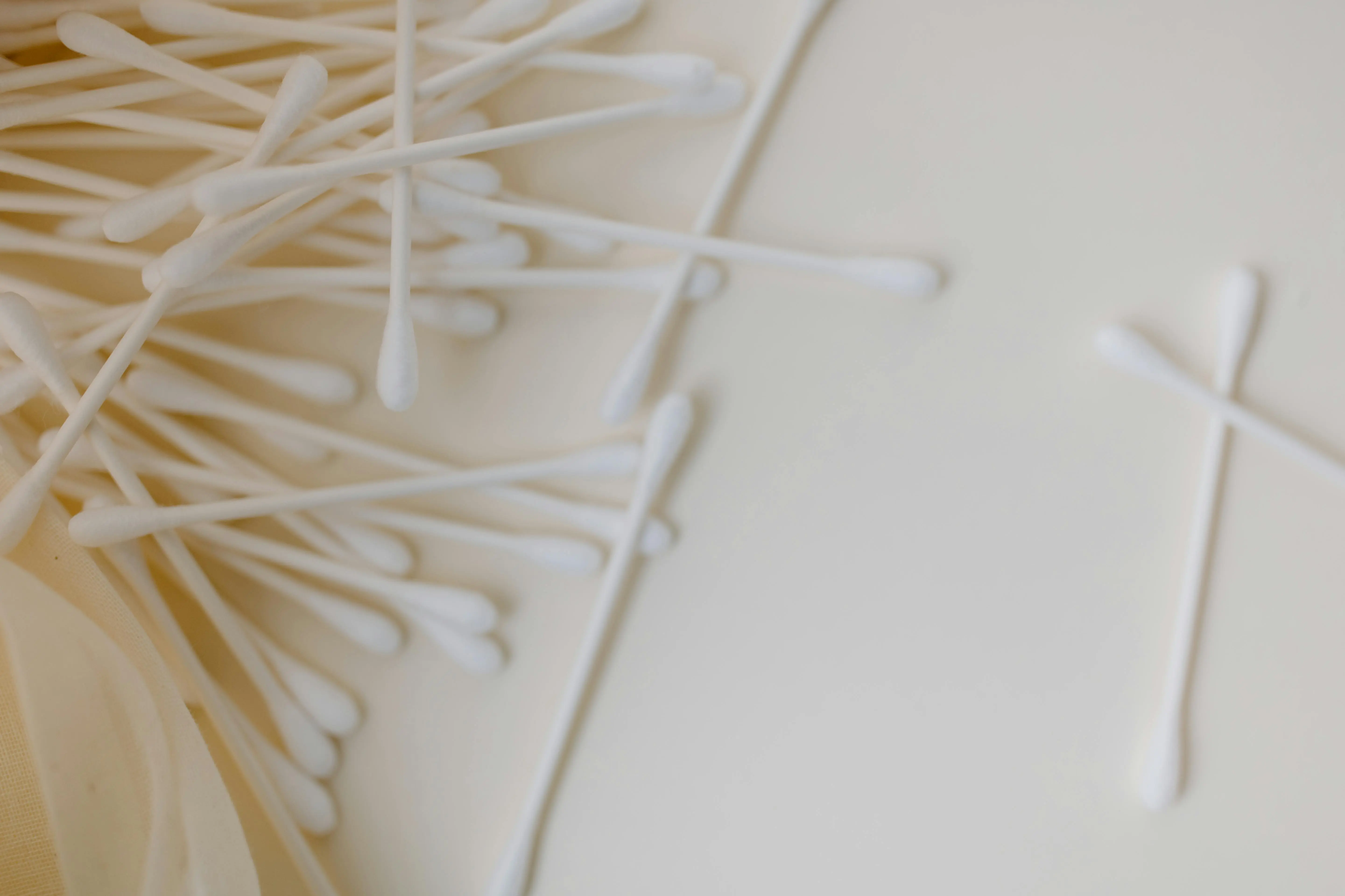 how to wash 100 cotton A detailed close-up of several cotton swabs scattered across a smooth, neutral surface, emphasizing cleanliness and hygiene.