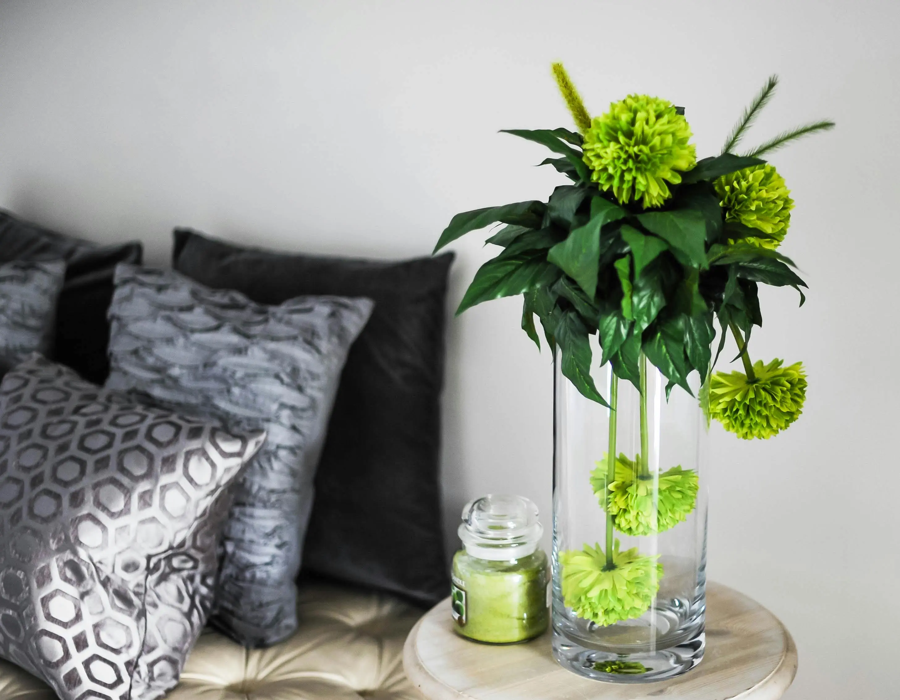 blue pillows Sophisticated room decor featuring green flowers in a vase, soft pillows, and chic glass jar.