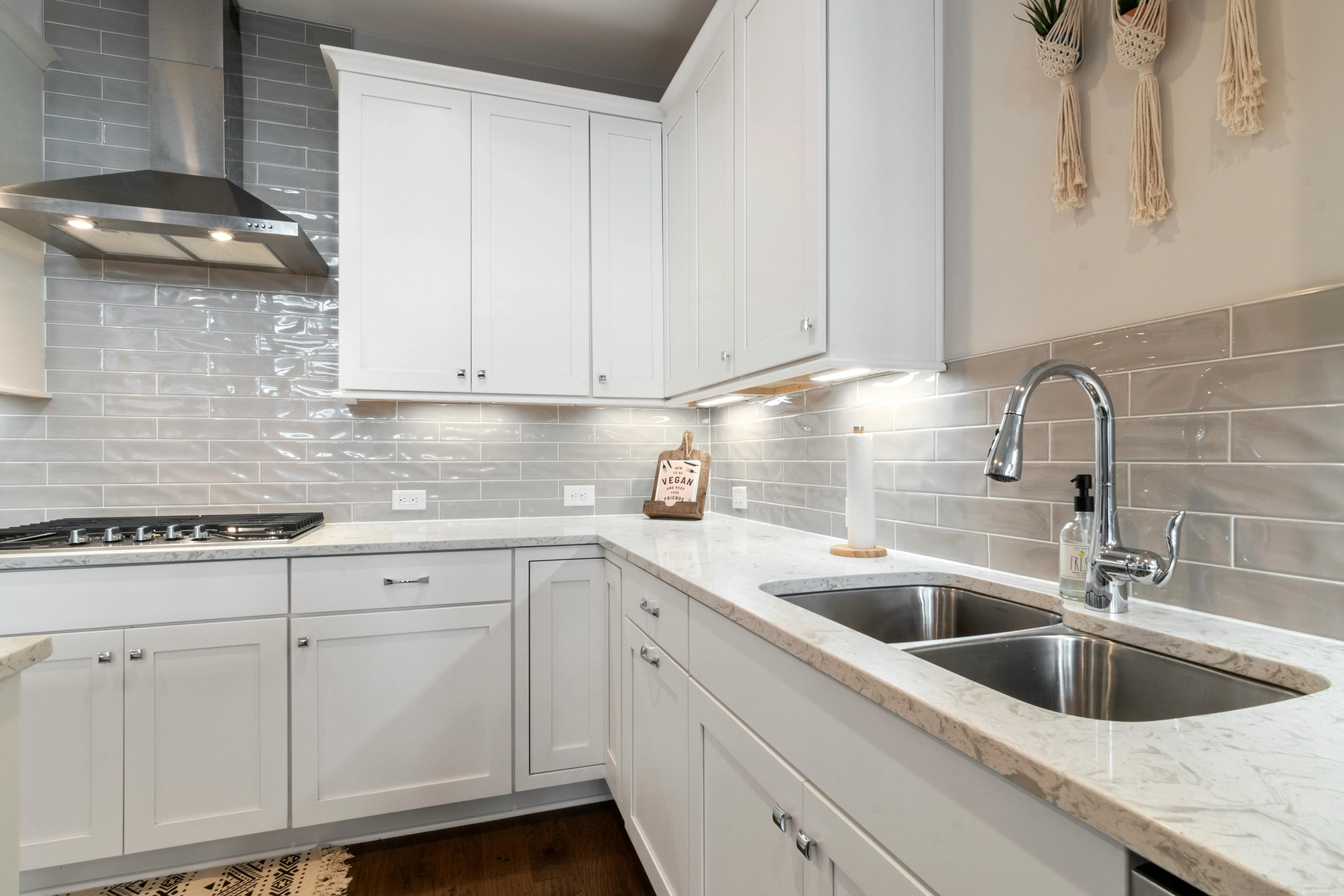 floral tile backsplash Sleek white kitchen with marble countertops and modern fixtures.