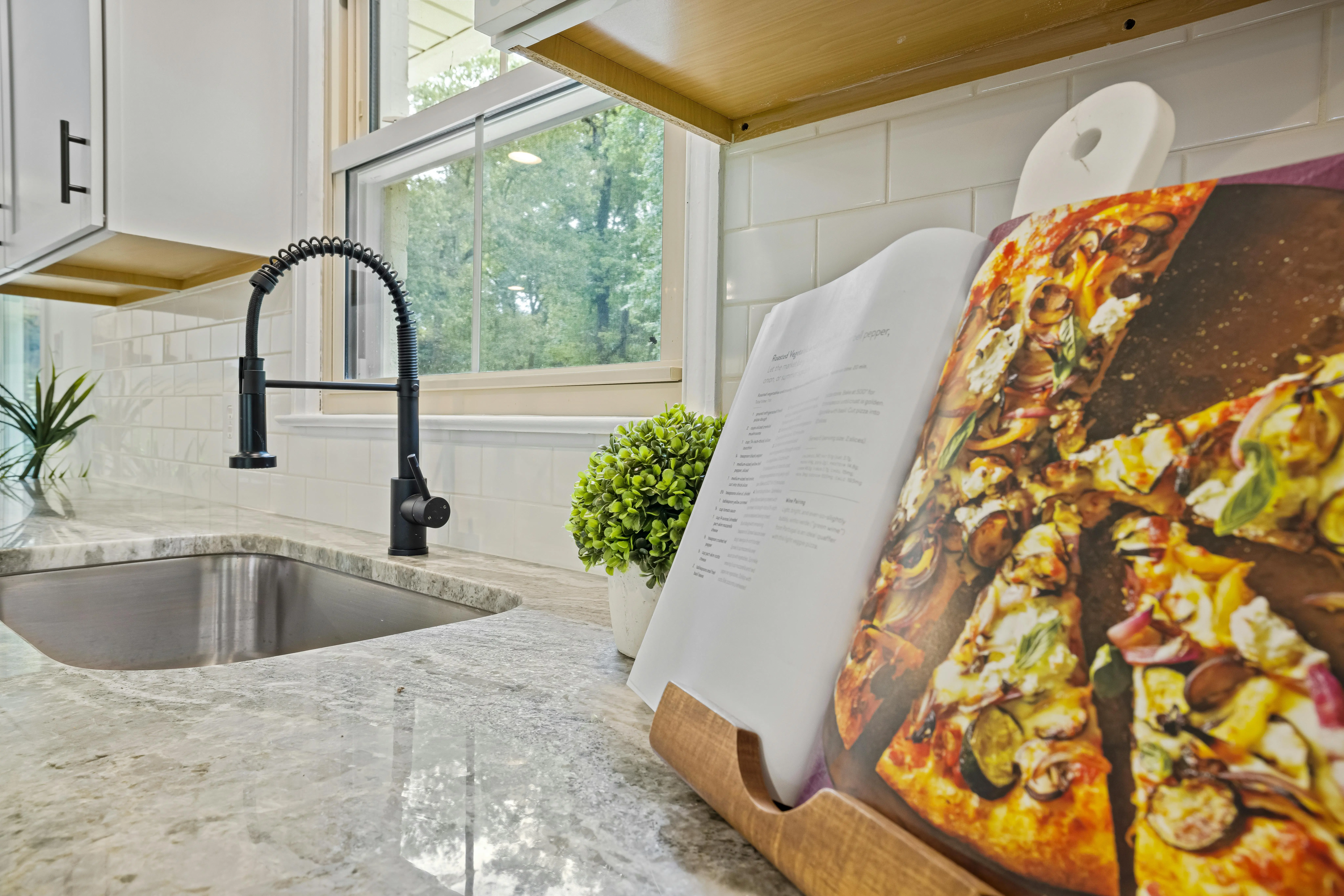 green quartz countertops Stylish kitchen featuring a marble countertop, modern sink, and an open cookbook with a pizza recipe.