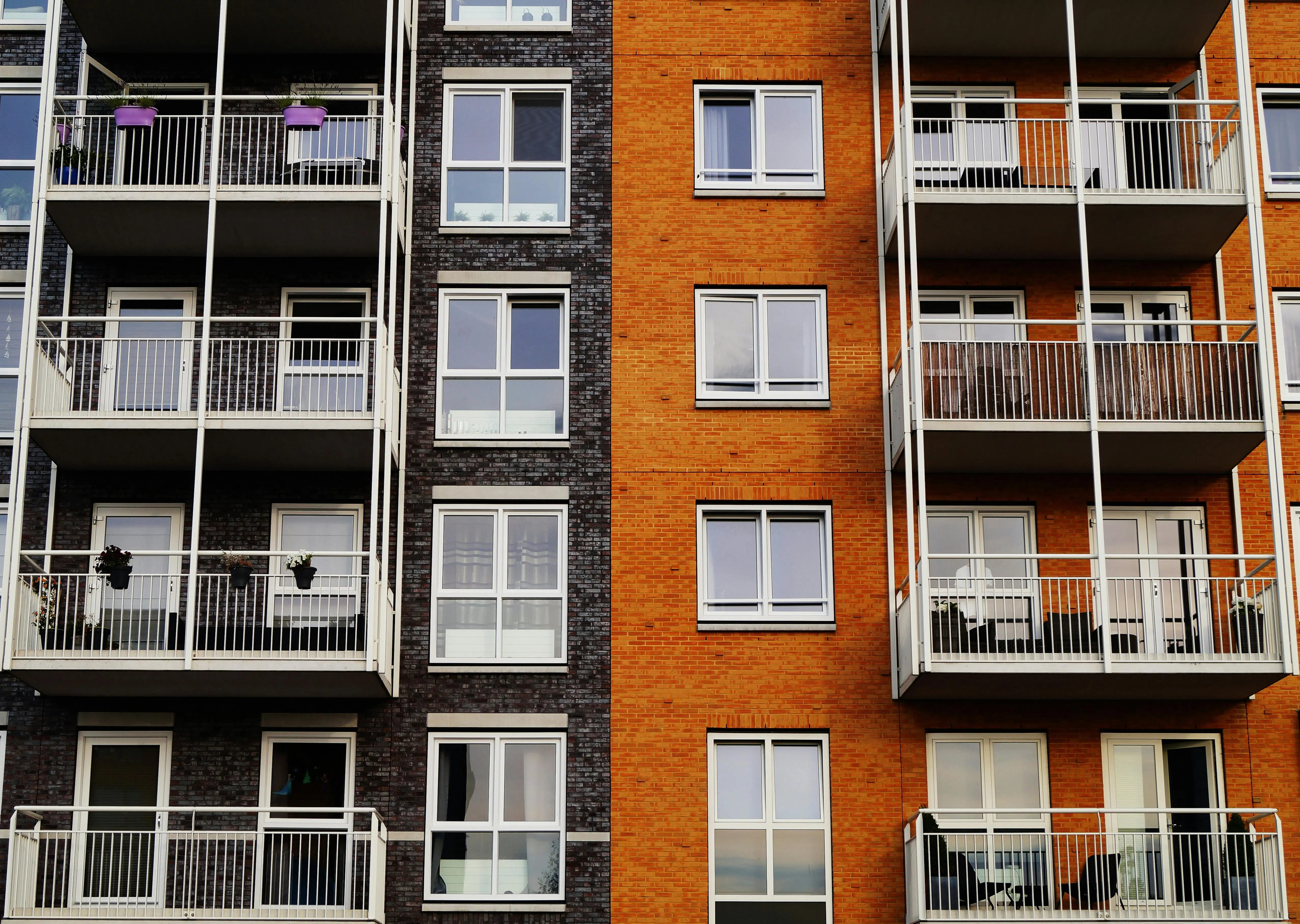 parts of a house exterior Detailed view of a modern apartment building's exterior with balconies and glass windows.