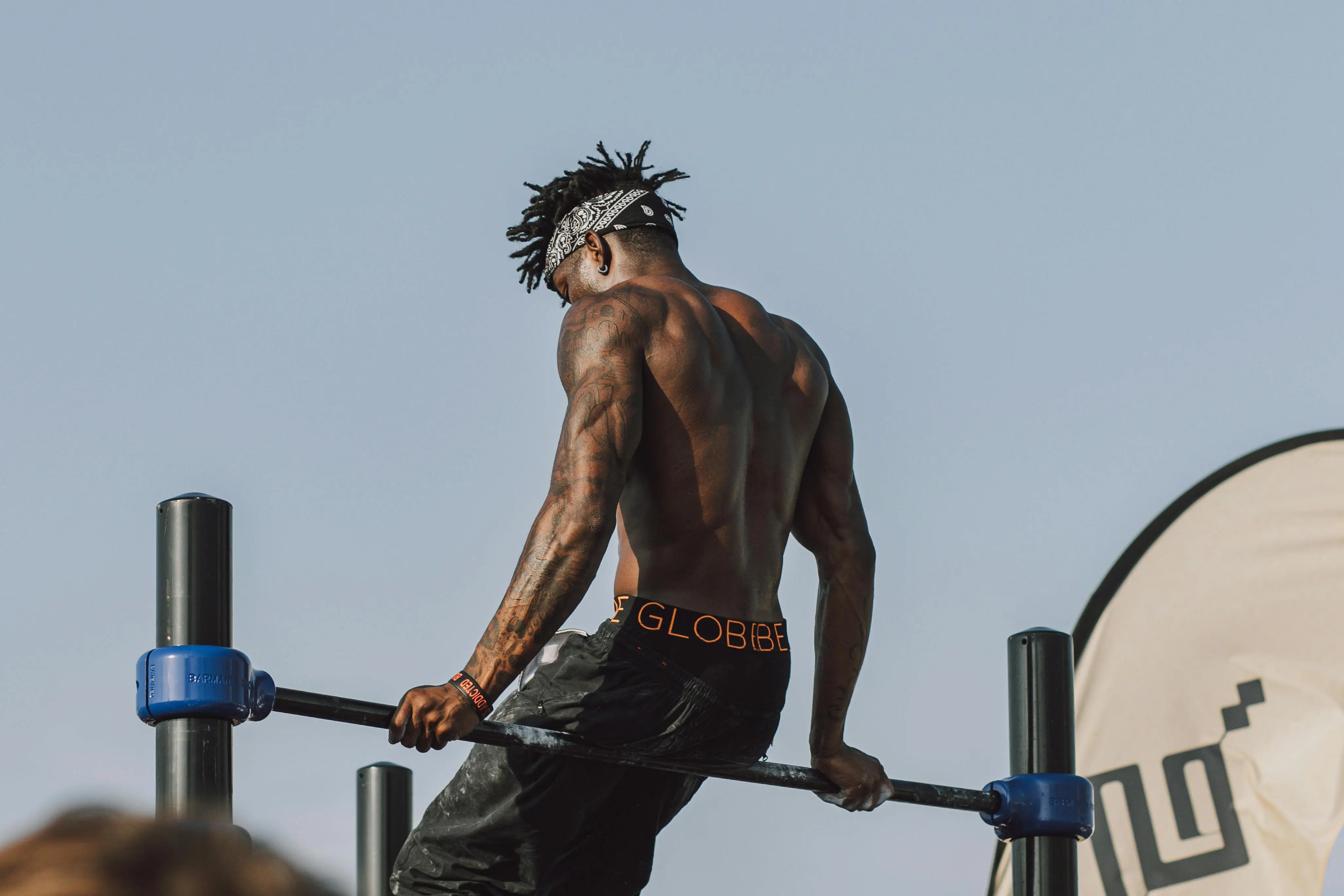 black drawer pulls A muscular man showcasing strength on a pull-up bar during an outdoor workout session.