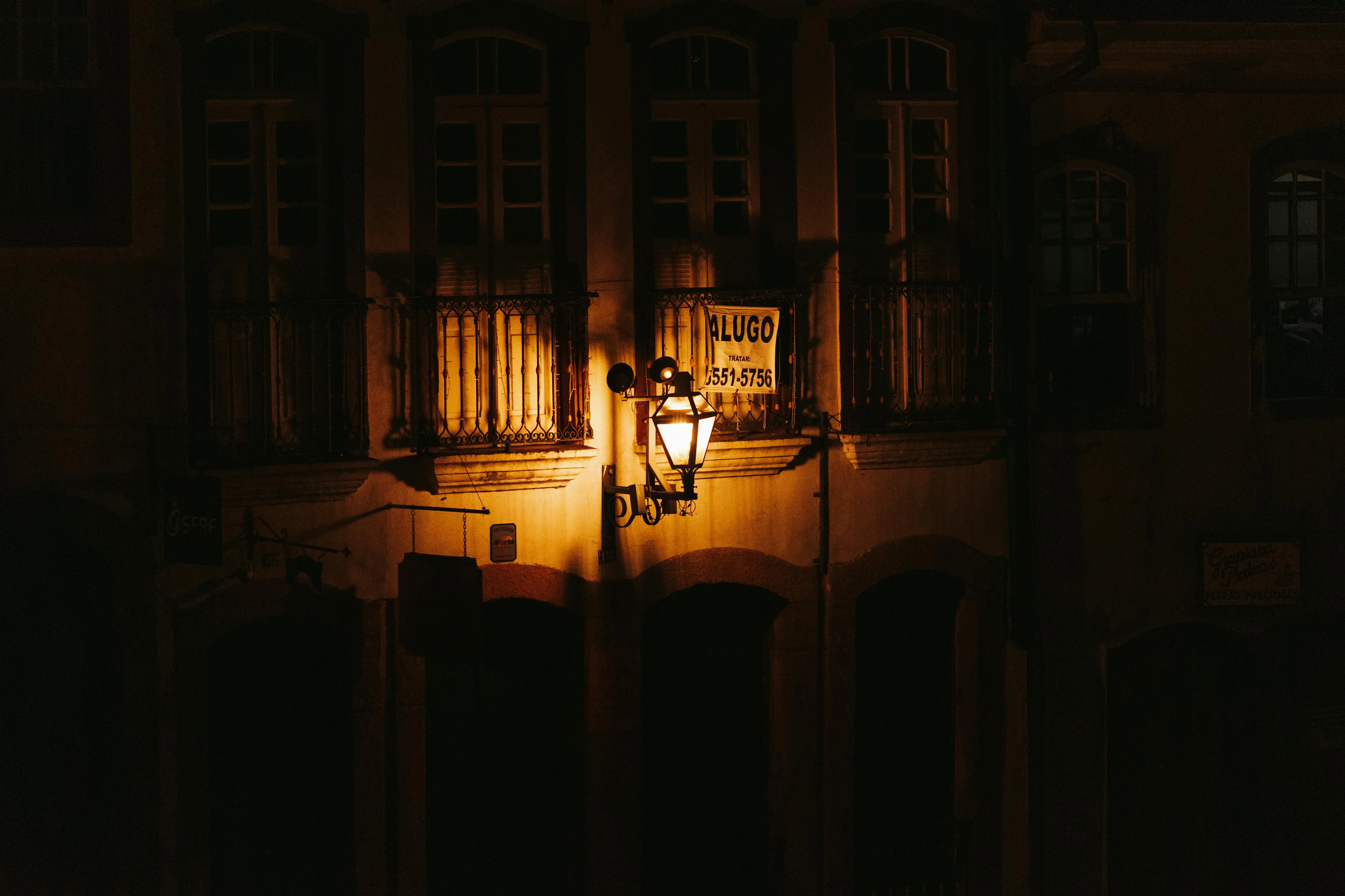 exterior wall sconce lights A historical building facade illuminated by a lantern at night, showcasing intricate balconies and windows.