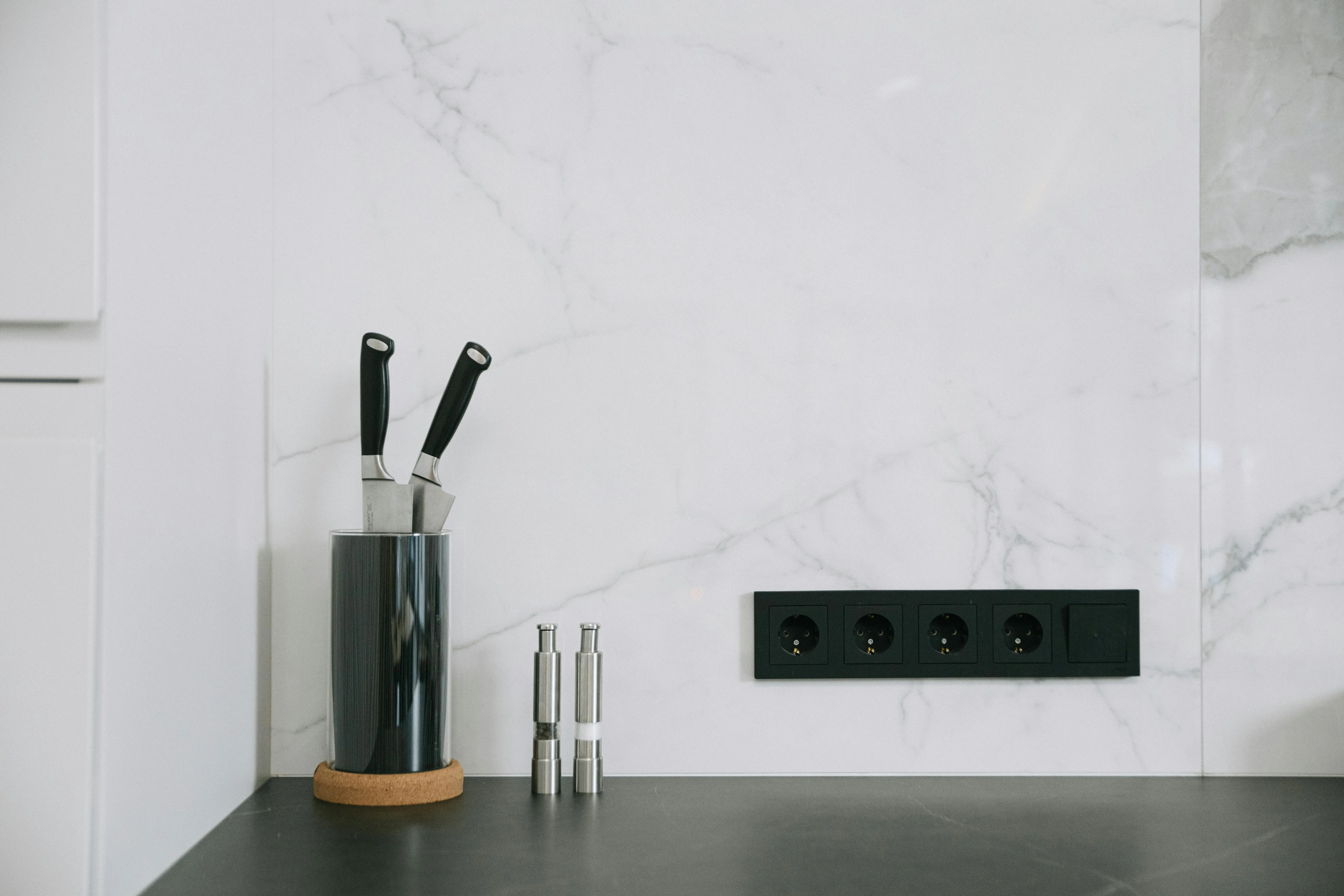 black and white backsplash Modern kitchen with marble backsplash, knife holder, and power outlets.