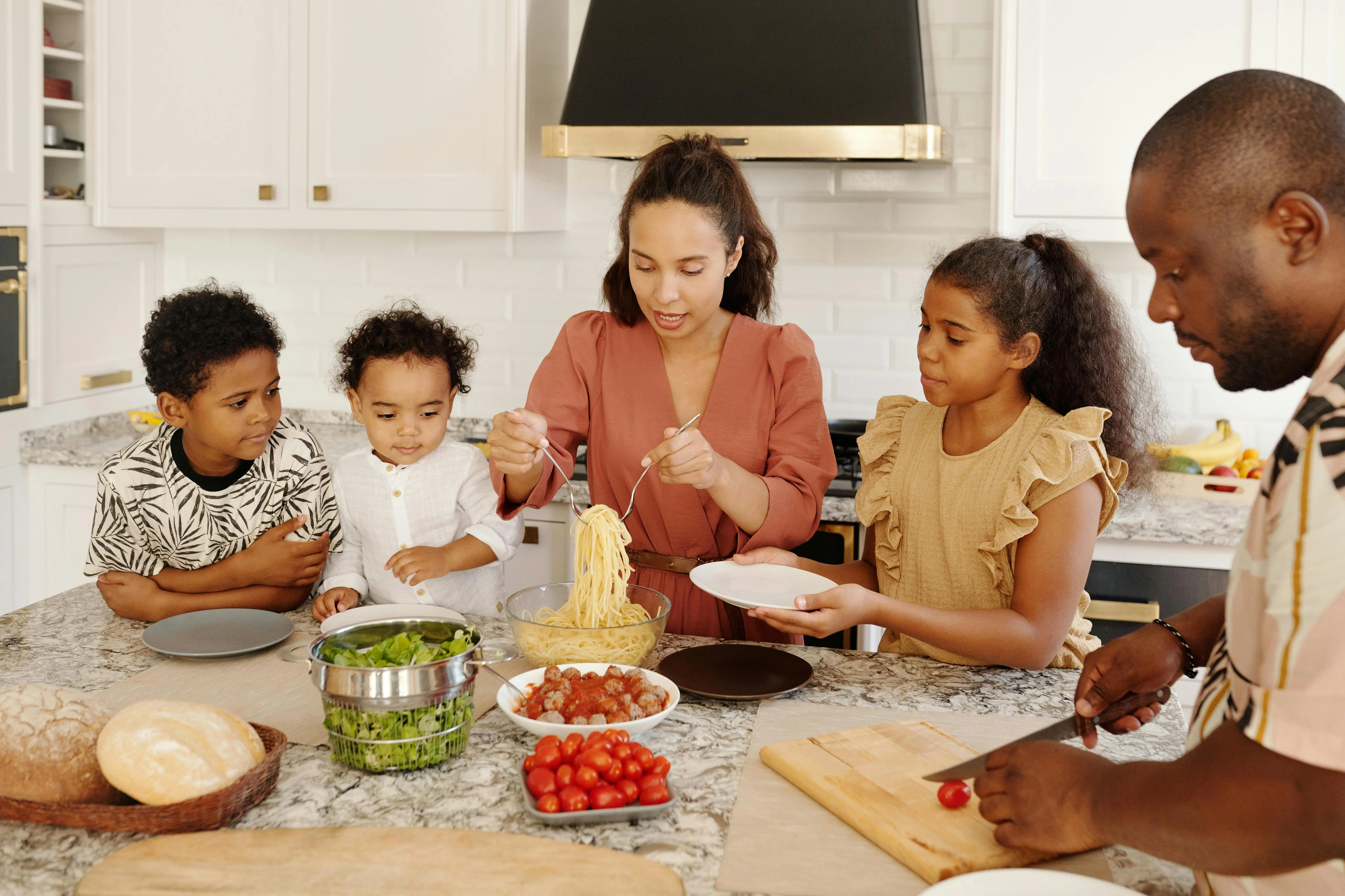 adjustable height coffee dining table Family enjoying a cooking session together in a modern kitchen, preparing pasta and vegetables.