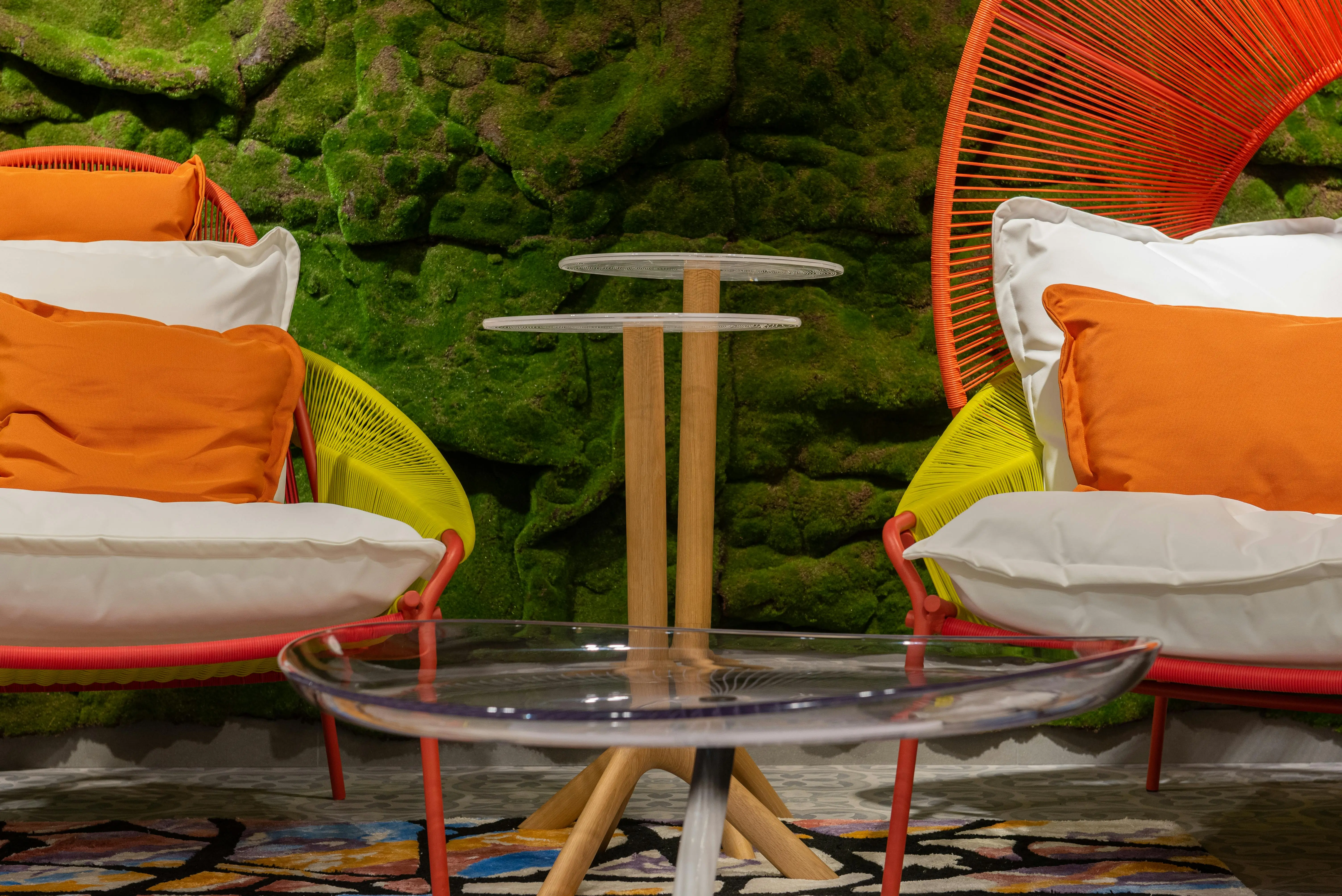set of 3 nest of tables A vibrant and cozy lounge setting with colorful chairs and a green moss wall.