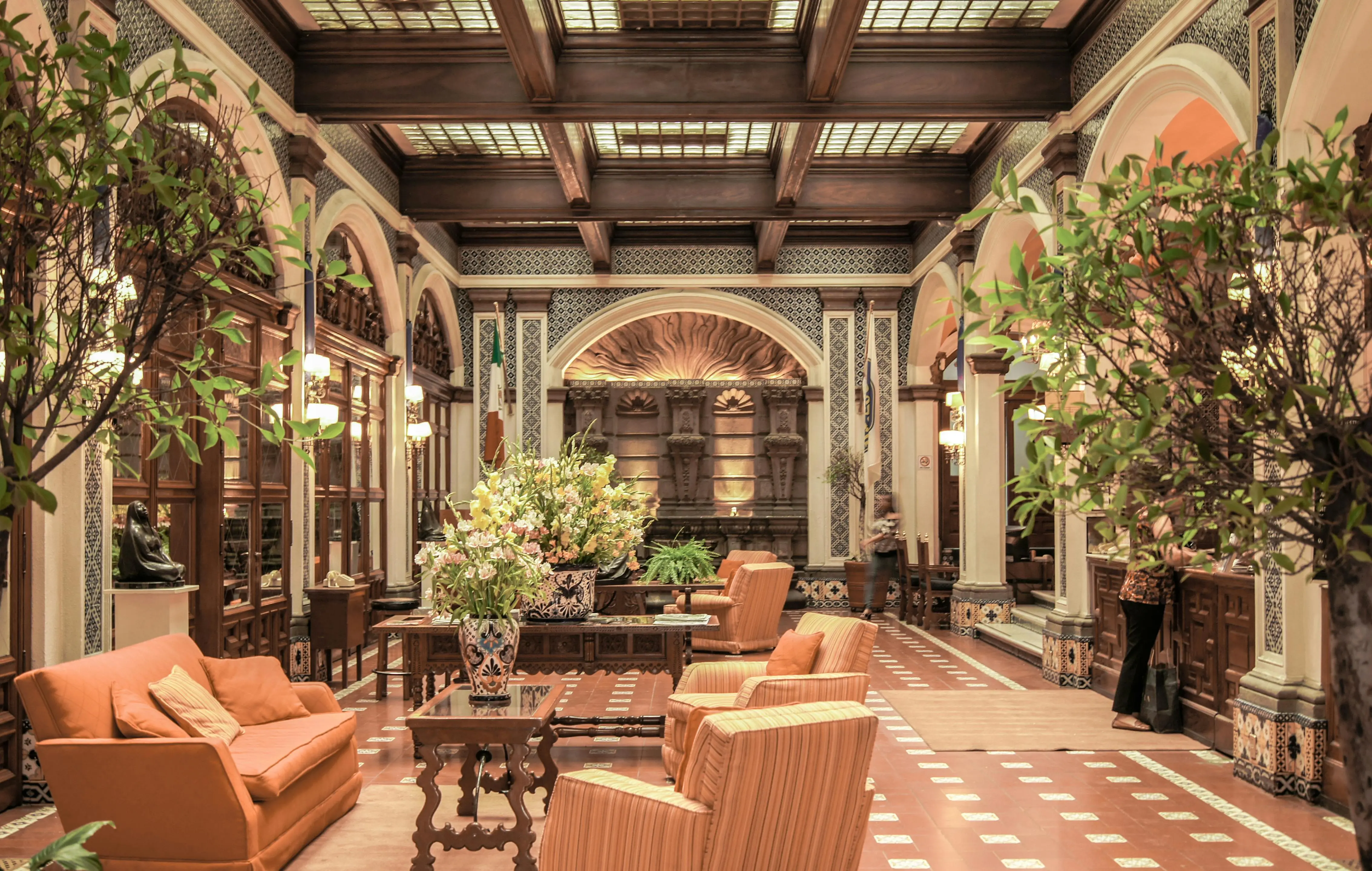 exclusive opulent interior designs A luxurious hotel lobby featuring elegant architecture, rich decor, and comfortable seating under a stained glass ceiling.