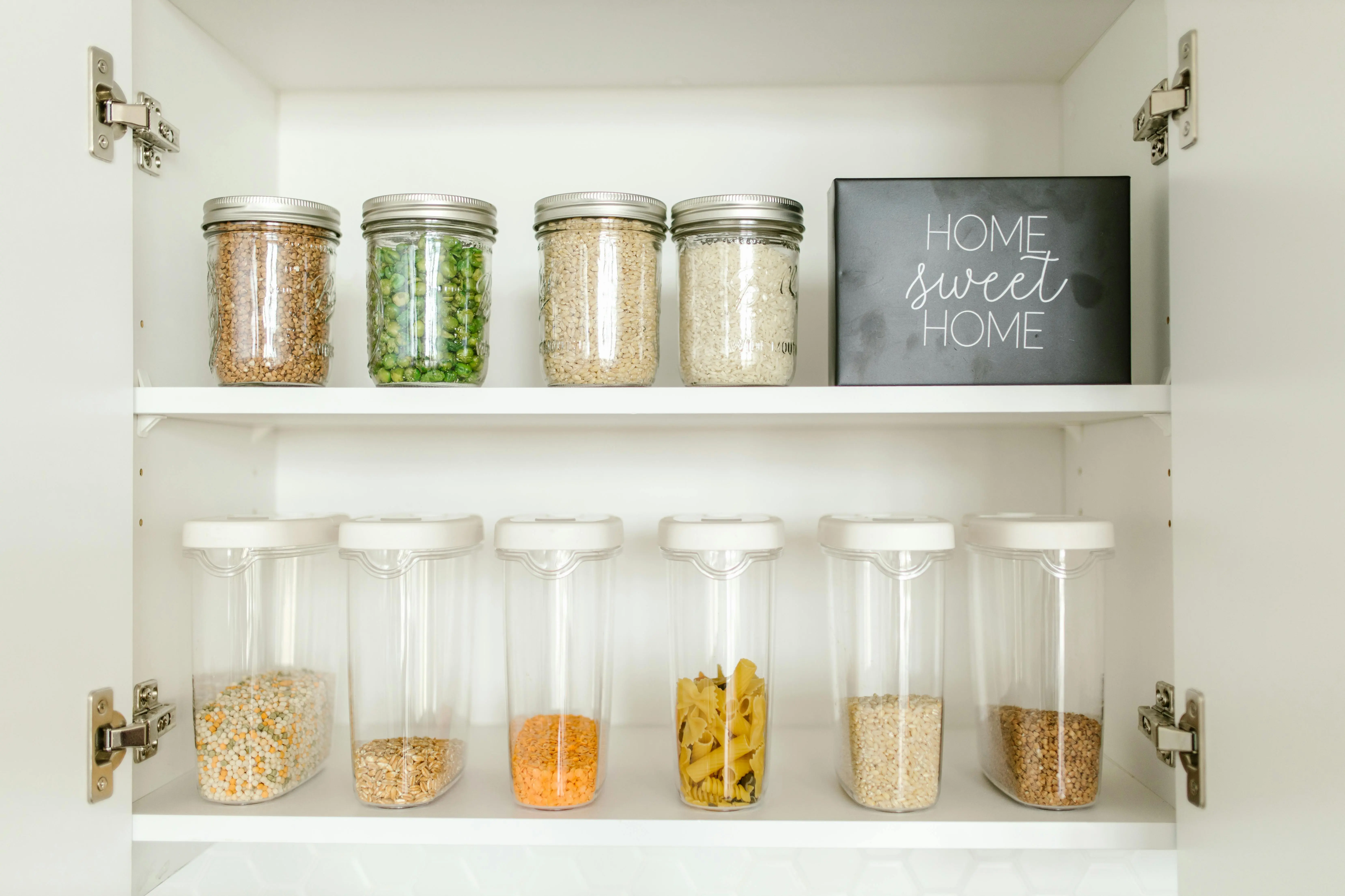 over door spice rack Neatly arranged glass and plastic jars containing grains and pasta in a kitchen cabinet.