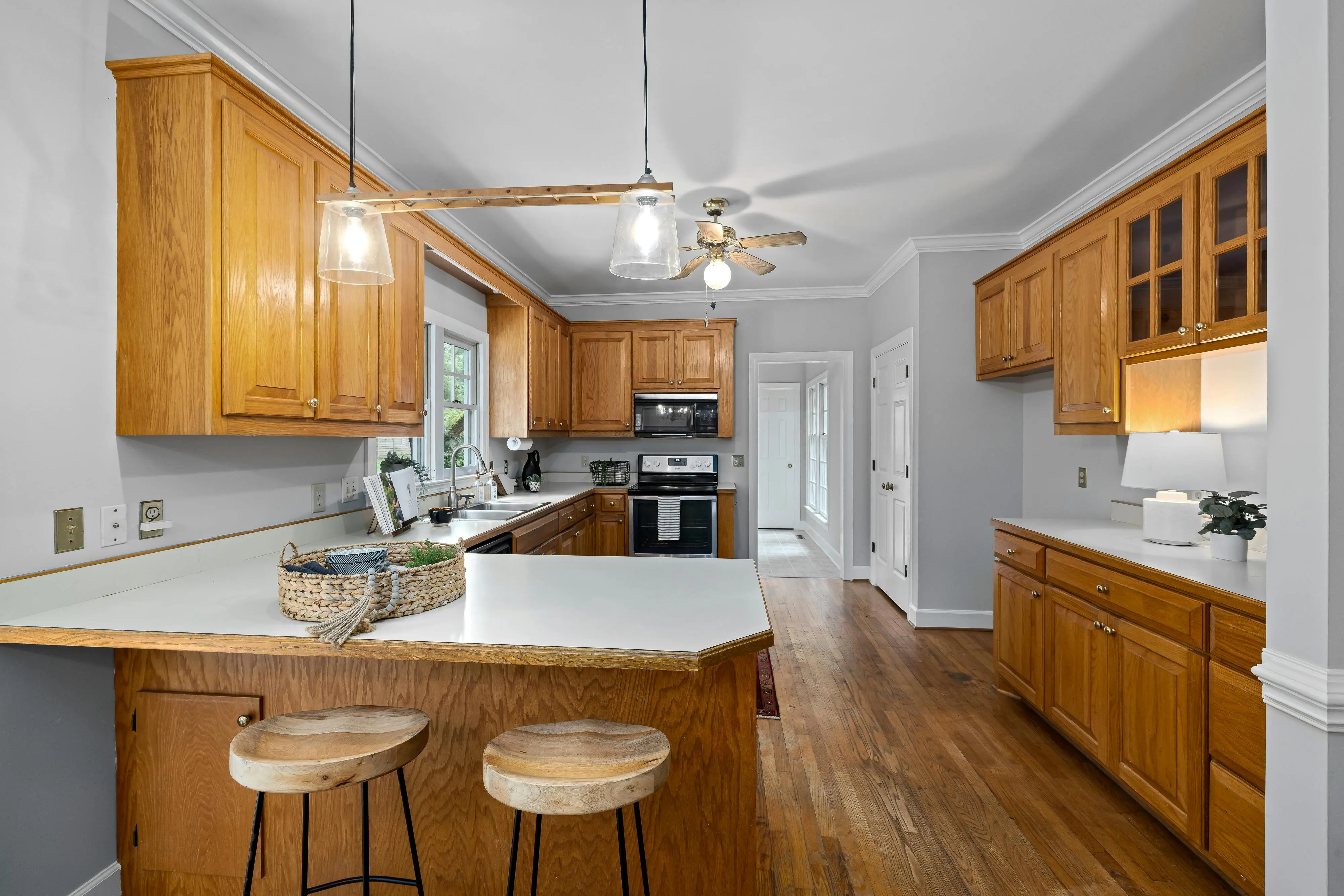 oak cabinets white Spacious kitchen with wooden cabinets, island seating, and modern appliances.