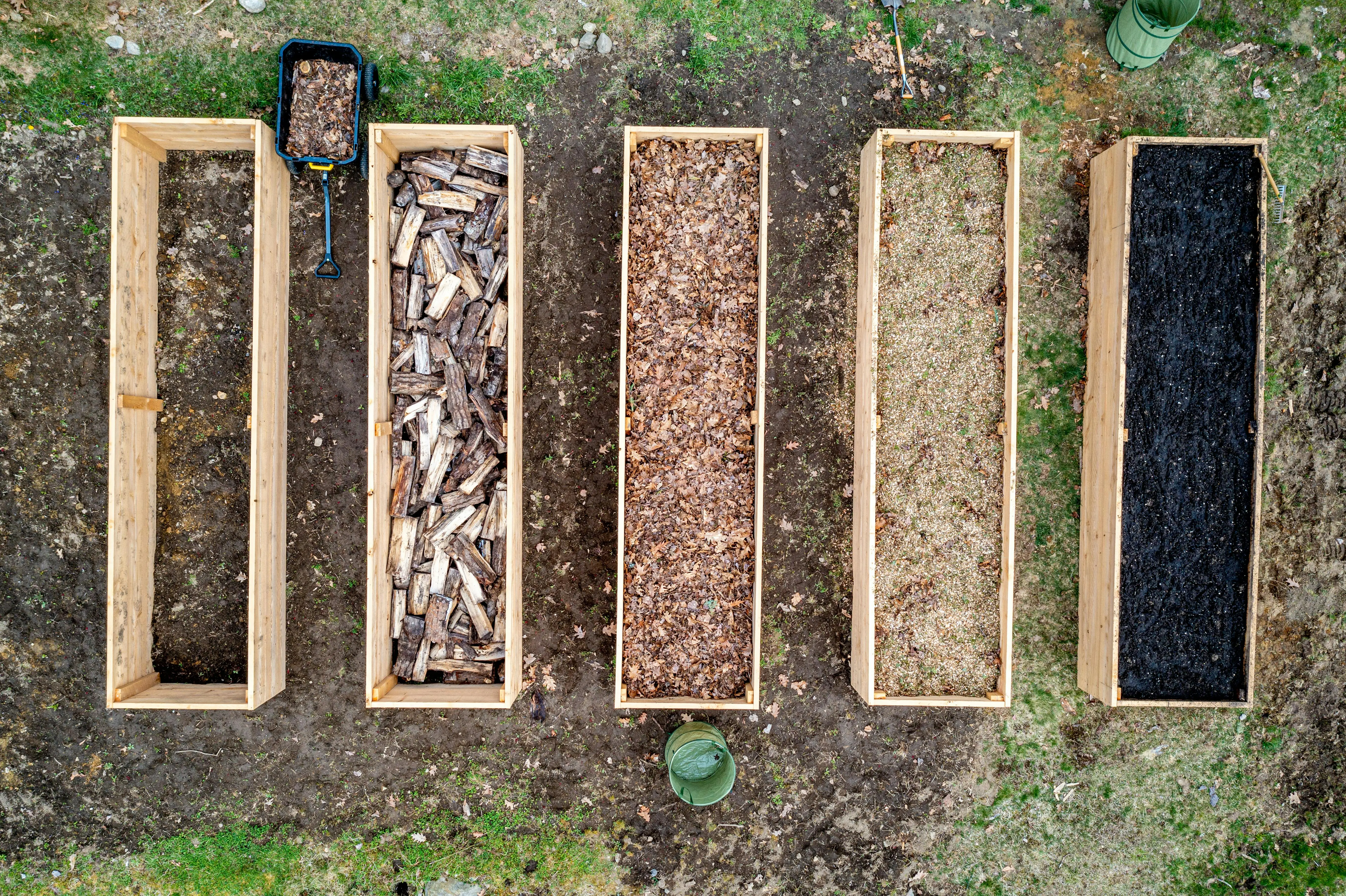 raised circular garden beds Top view of wooden boxes with piles of firewood wood chips sawdust and coal placed on ground in agricultural plantation