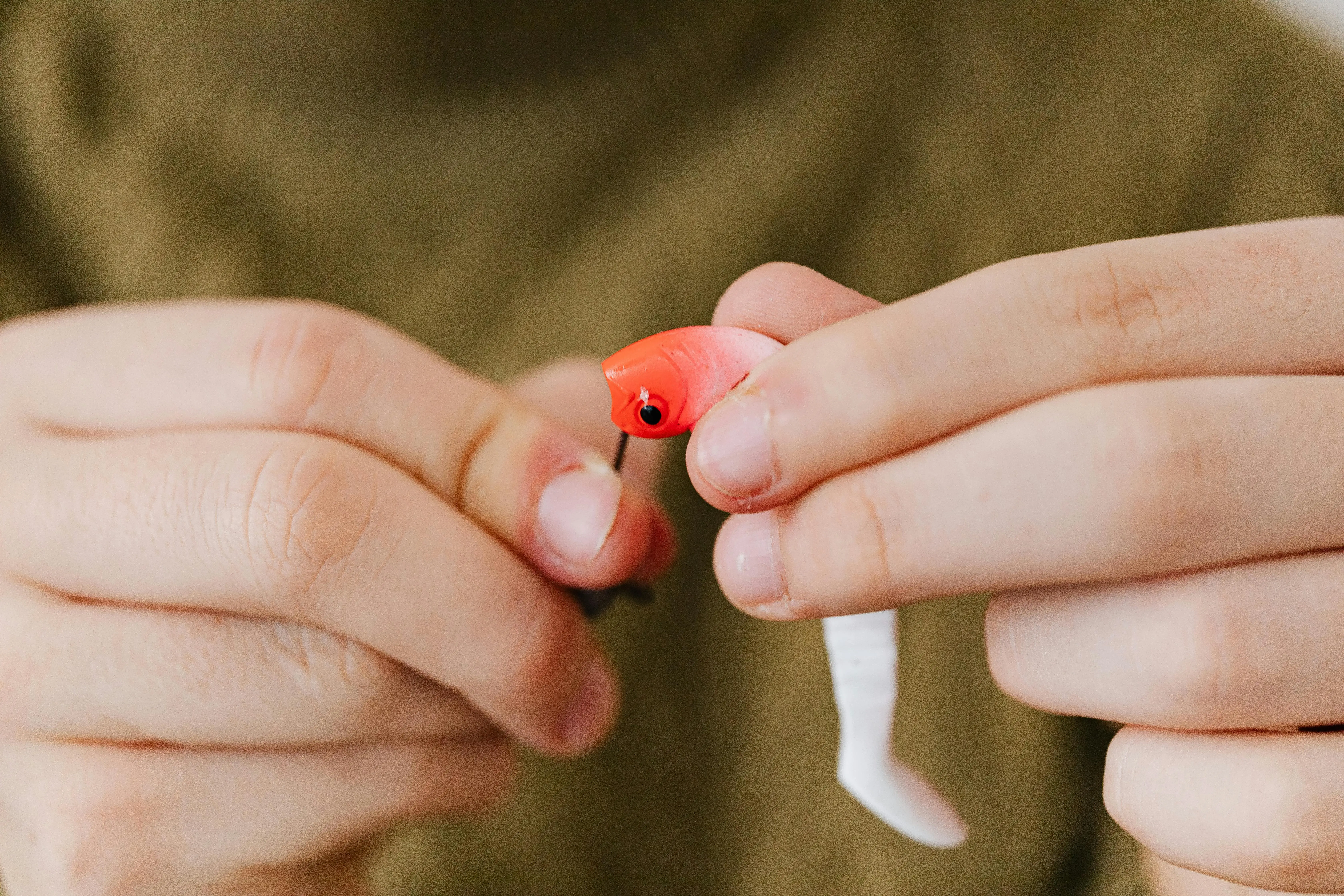 farnam just one bite ii rat Detailed view of hands assembling a red fishing lure, highlighting fishing as a hobby.