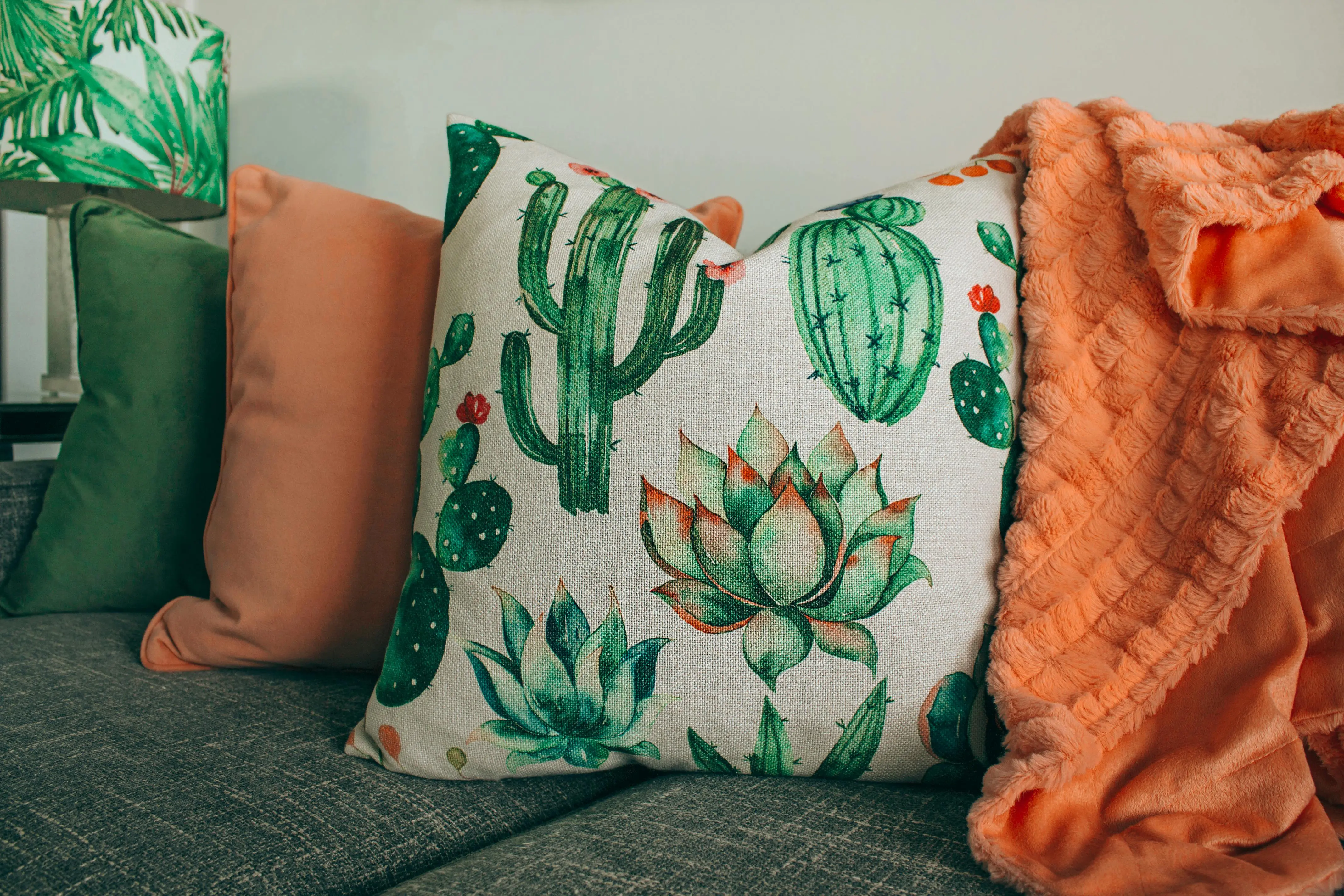blue and white pillows A stylish living room setup with cactus-themed pillow and soft orange blanket.