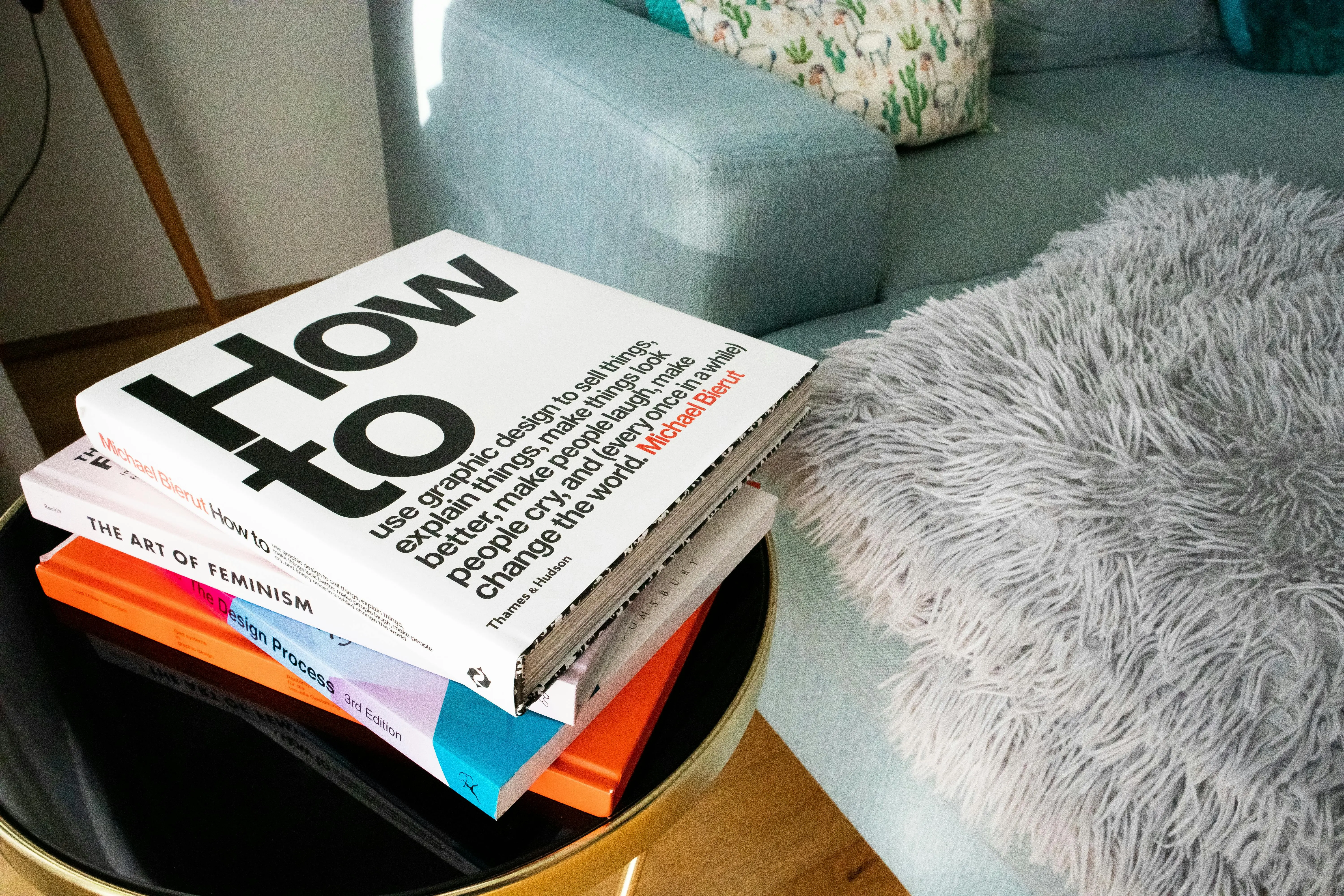 blue pillows Modern living room with a pile of design and art books on a black coffee table, next to a cozy couch with pillows.