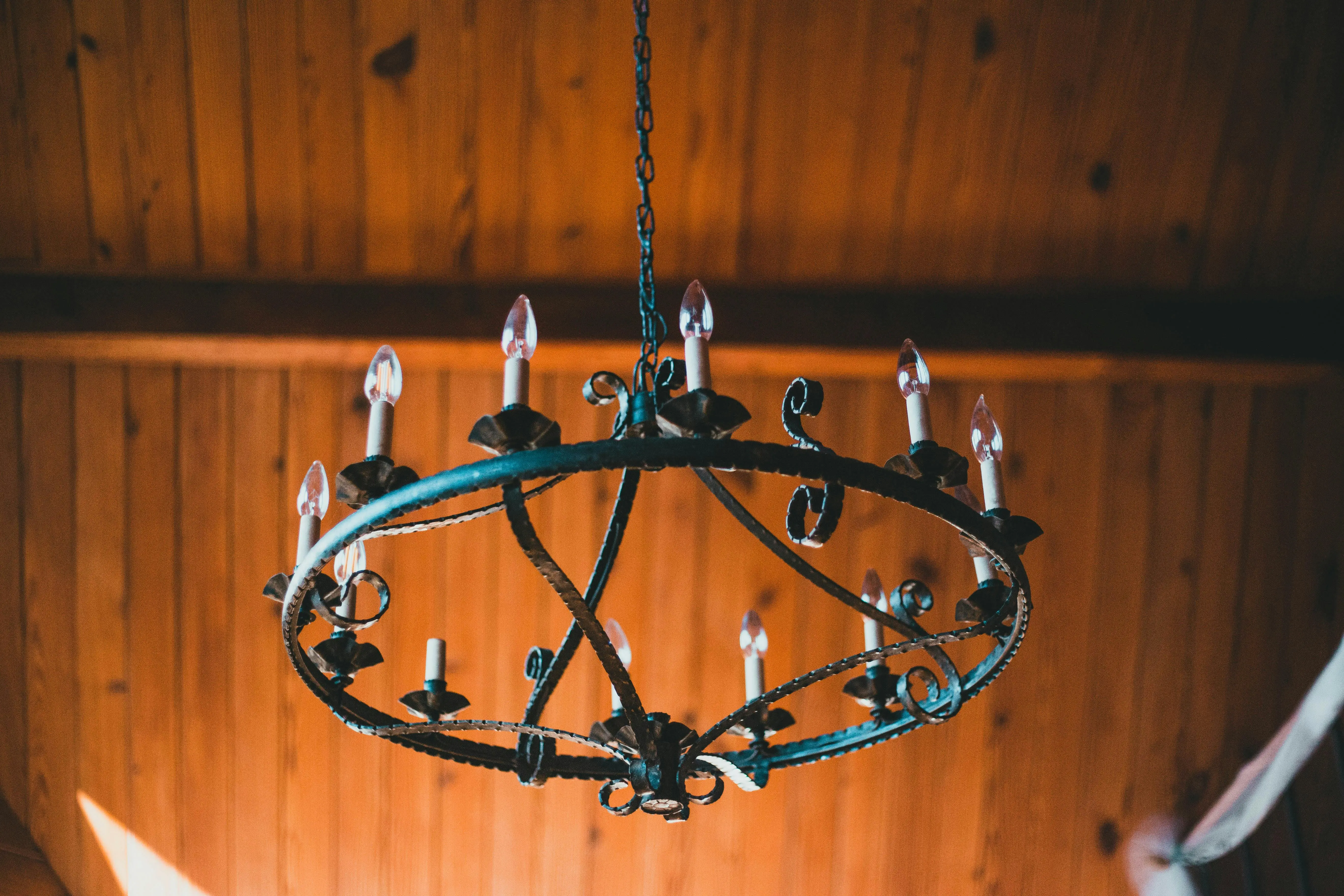suspended ceiling alternatives A vintage metal chandelier hanging from a warm wooden ceiling, creating an antique ambiance.