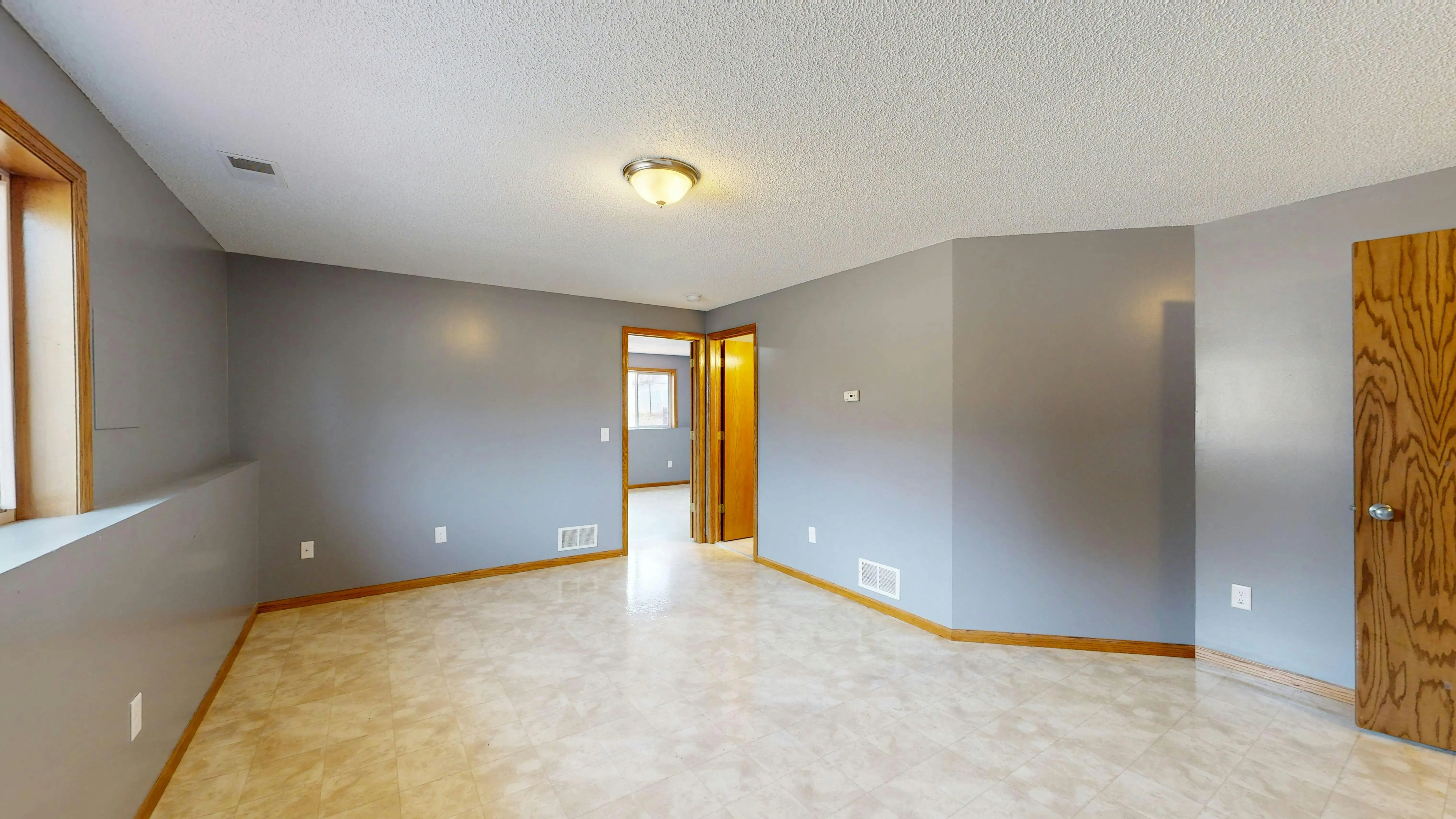 tiny house on foundation Bright empty room with gray walls, wooden trim, and a single light fixture.