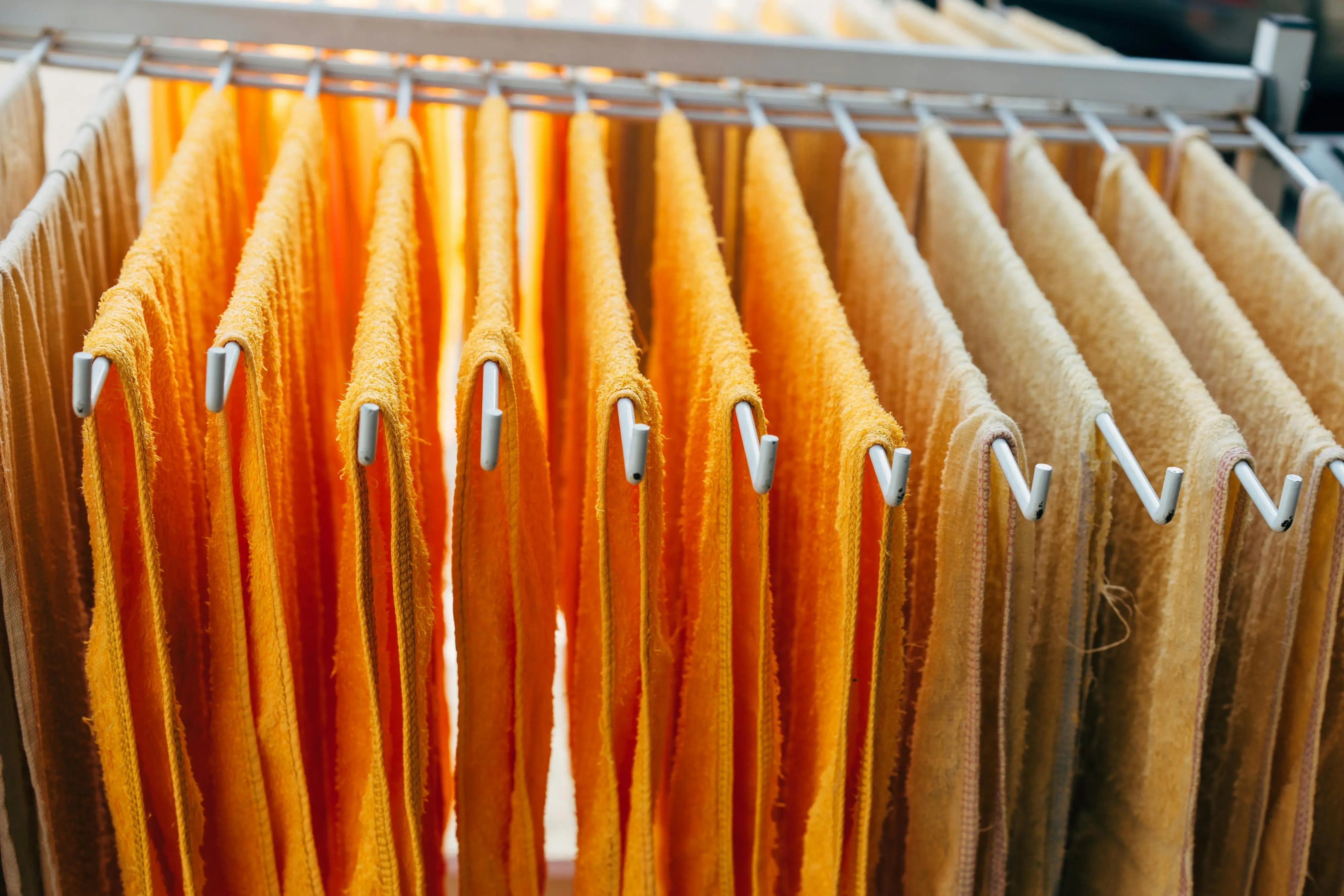 and paper towels Vibrant orange and beige towels neatly hang on a drying rack indoors.