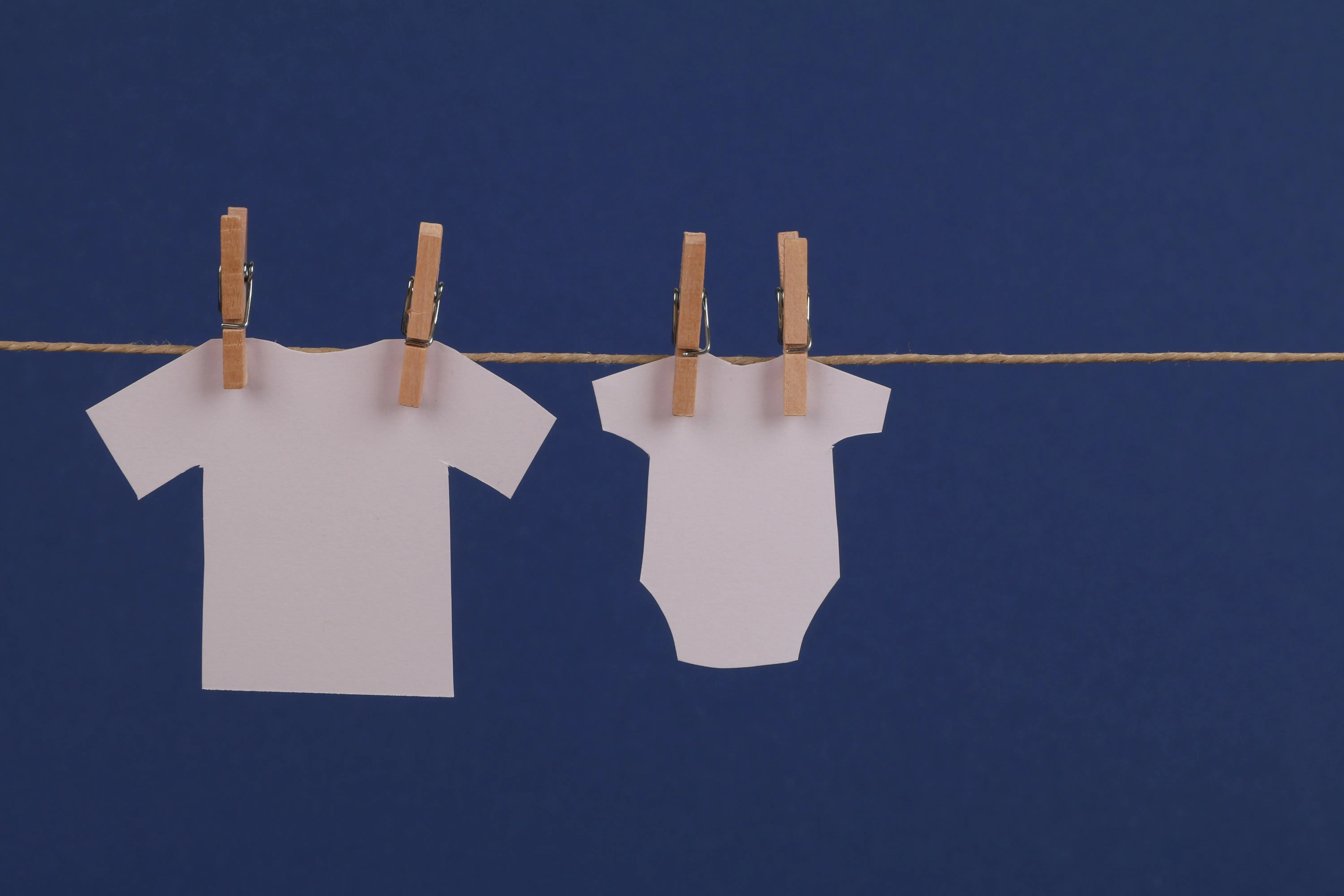 what can i use instead of laundry detergent Paper cutouts of clothes hanging with clothespins on a string against a blue background.