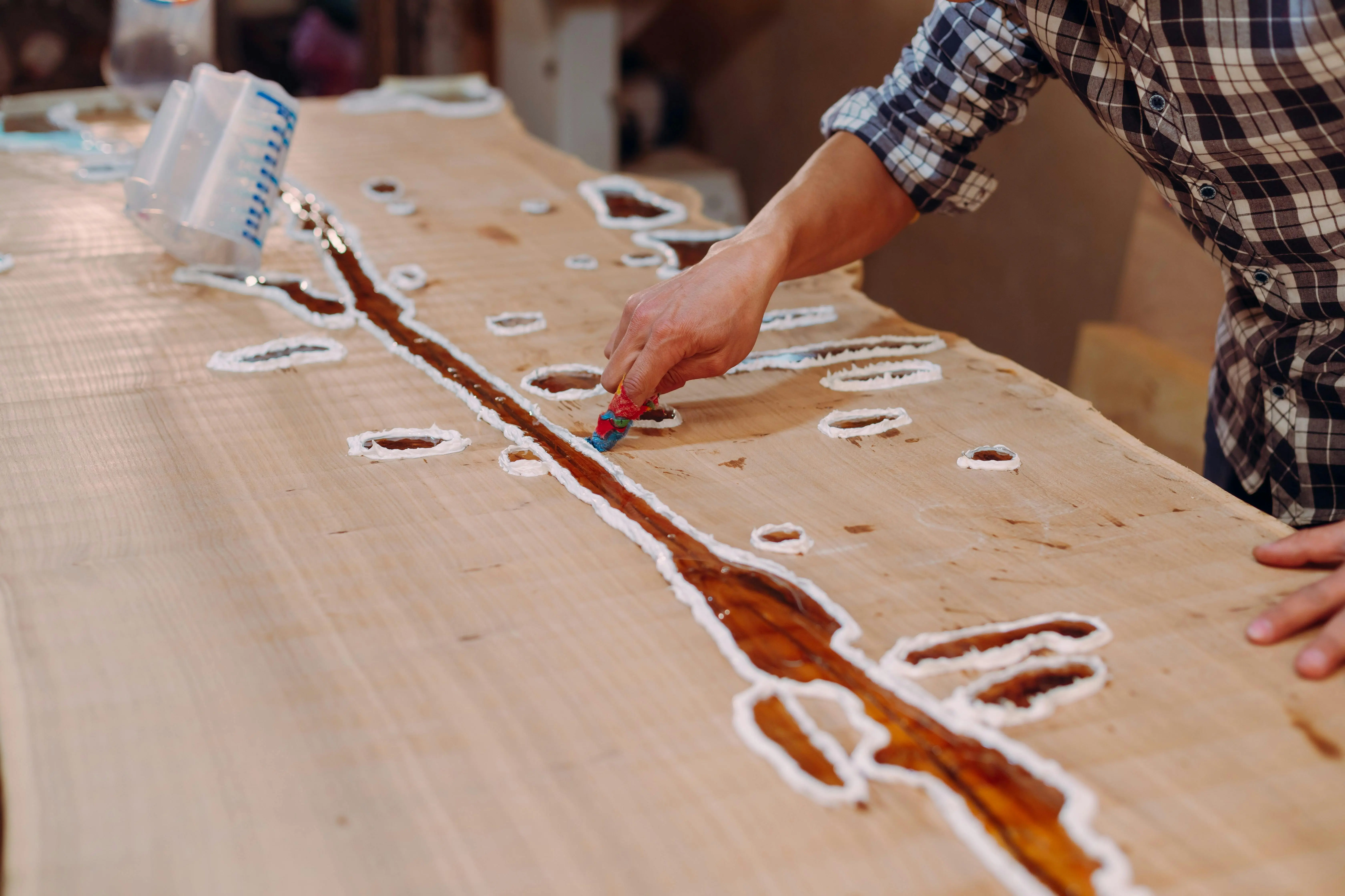 diy garage floor coating A skilled craftsman applying resin on a wooden table in a workshop setting.