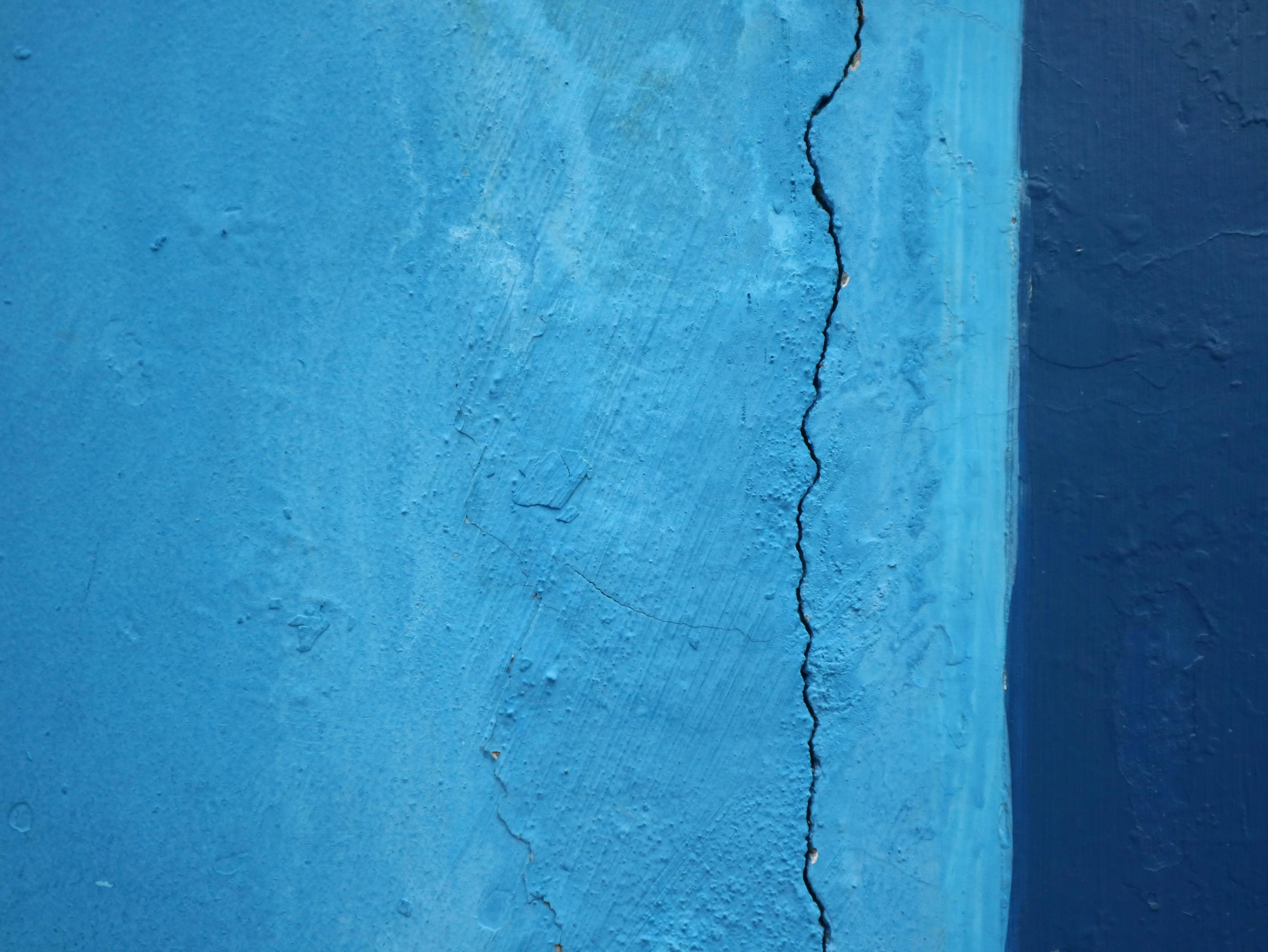 crack in bathtub Detailed close-up of a cracked blue wall texture, revealing surface imperfections.