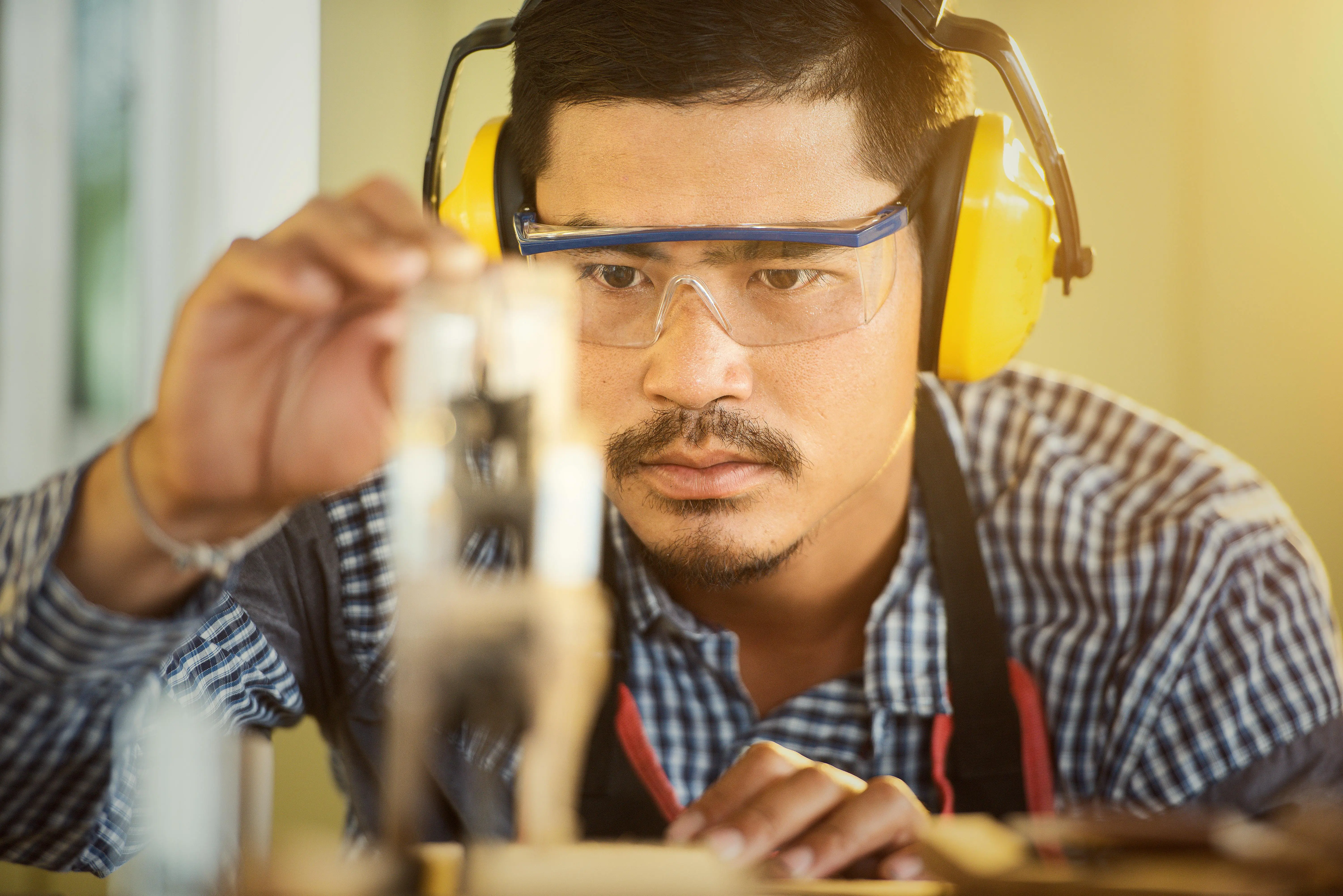 carpenter with tools Carpenter wearing protection gear measuring wood in a workshop with great focus and precision.