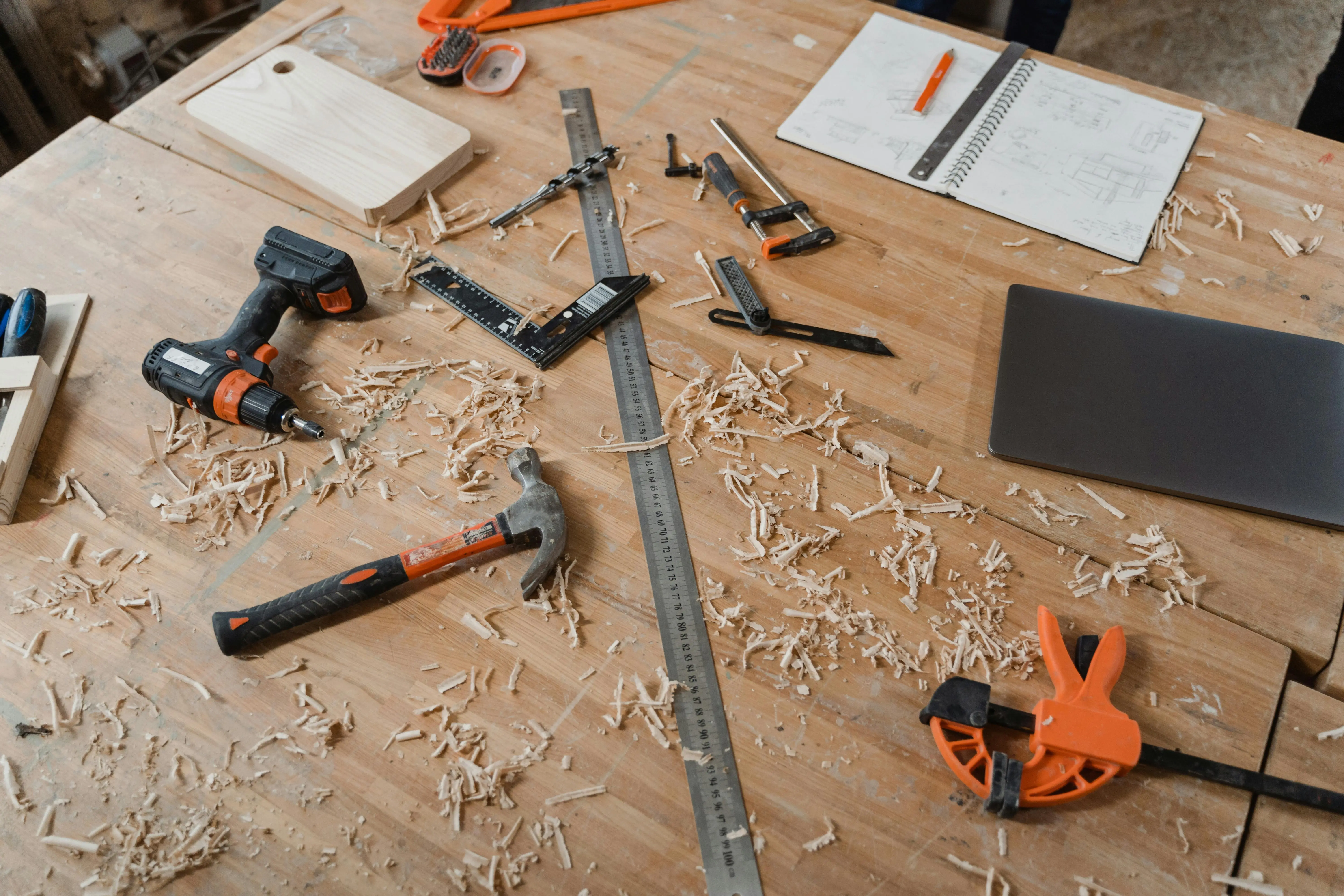 carpenter with tools A workbench with various woodworking tools alongside sketches and wood shavings, indicating an active project.