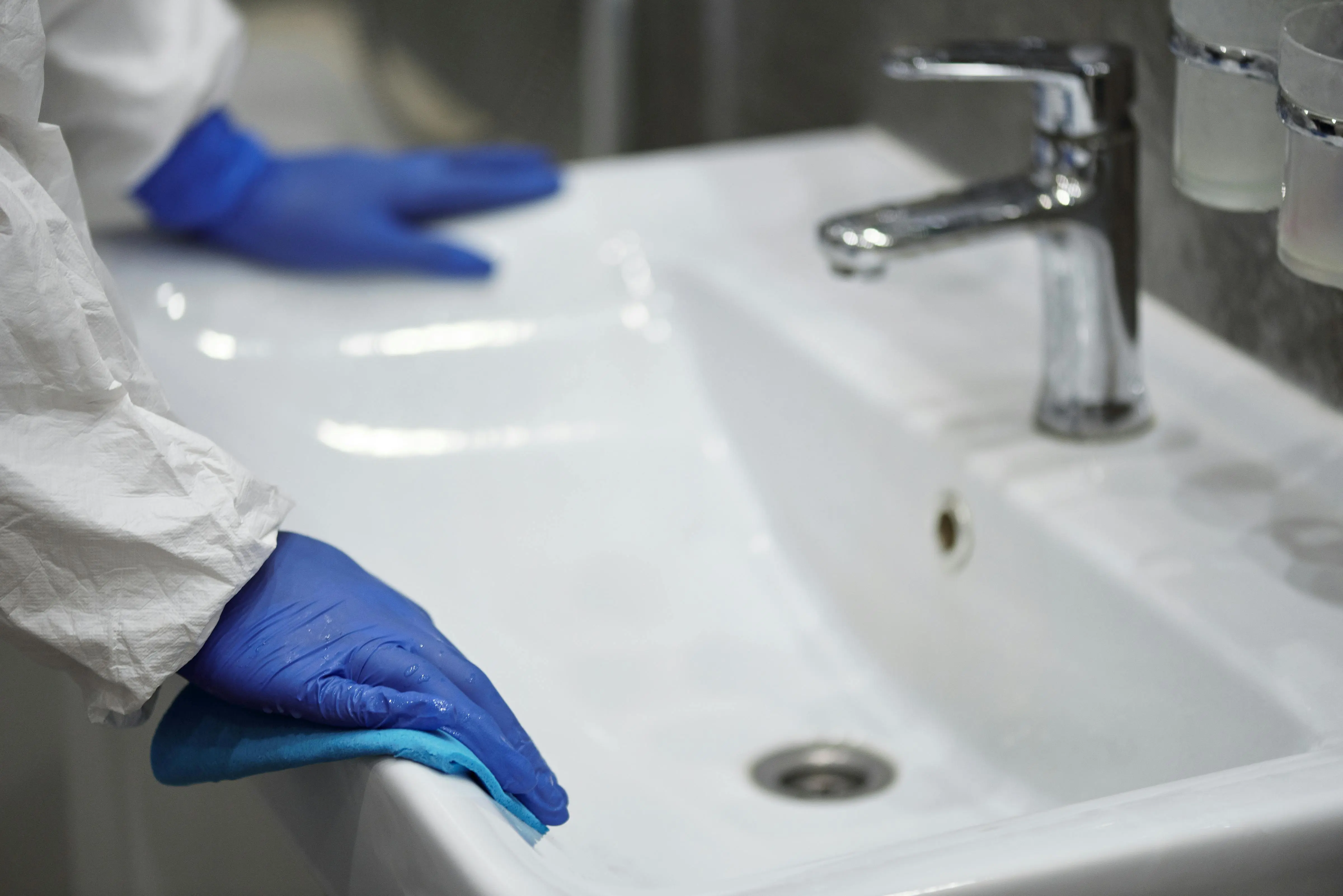 get rid of calcium deposit marks sink Close-up of a gloved professional cleaning a sink for sanitation.