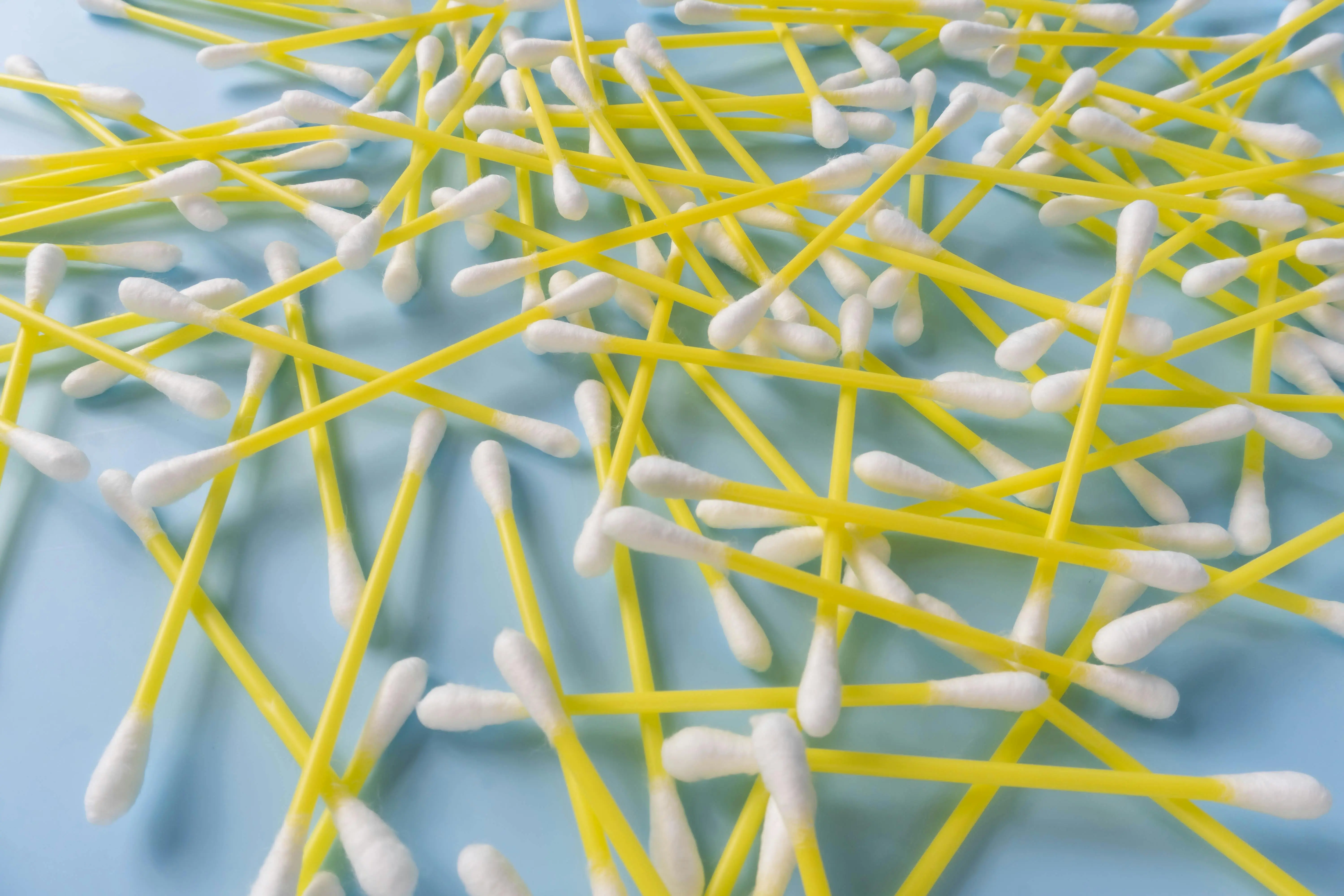 how to get grass stains out of jeans Scattered yellow cotton swabs on a soft blue surface. Perfect for health and hygiene themes.