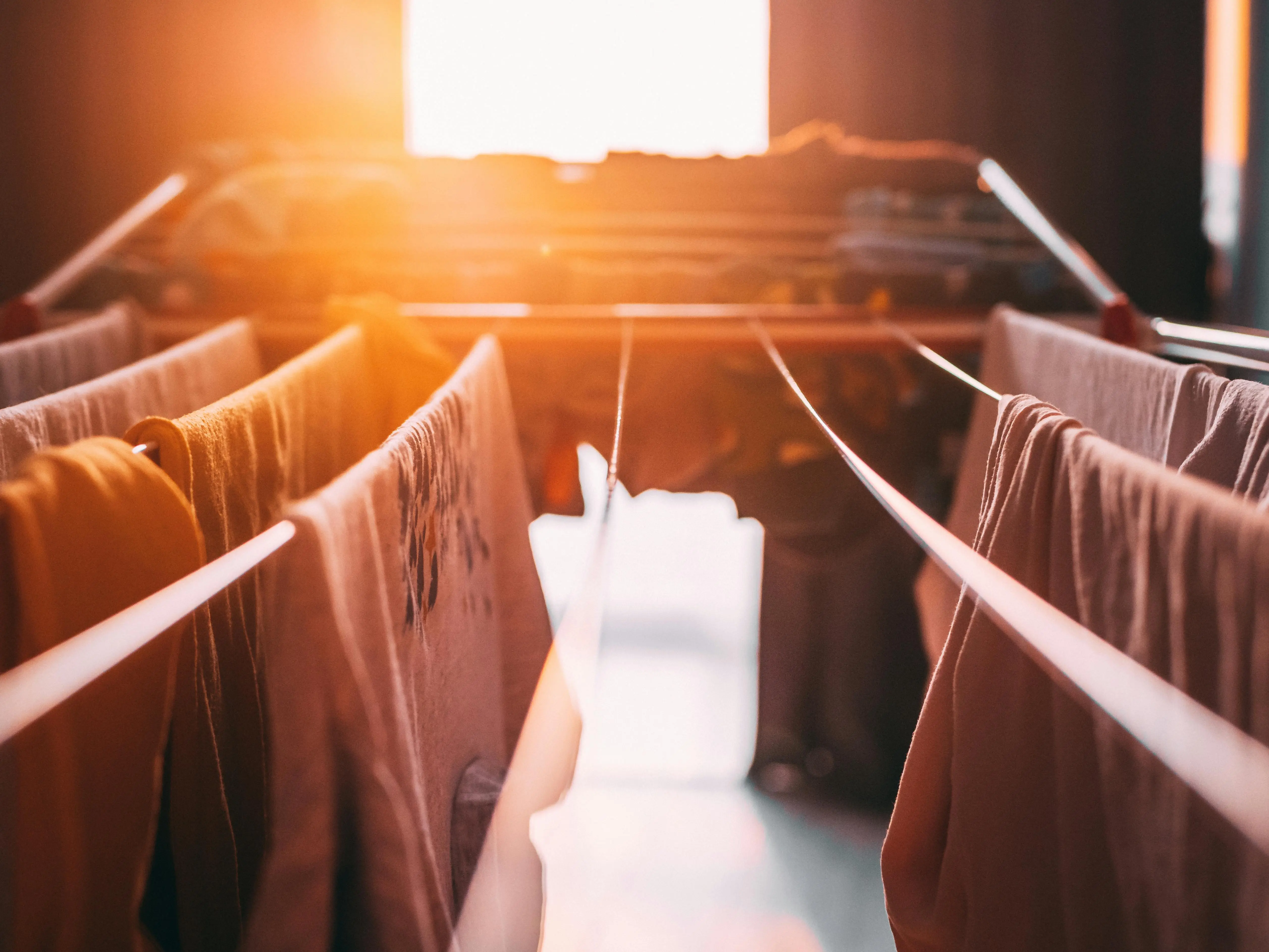 how to get period blood out of clothes Laundry drying indoors under warm sunset hues, creating a cozy atmosphere.