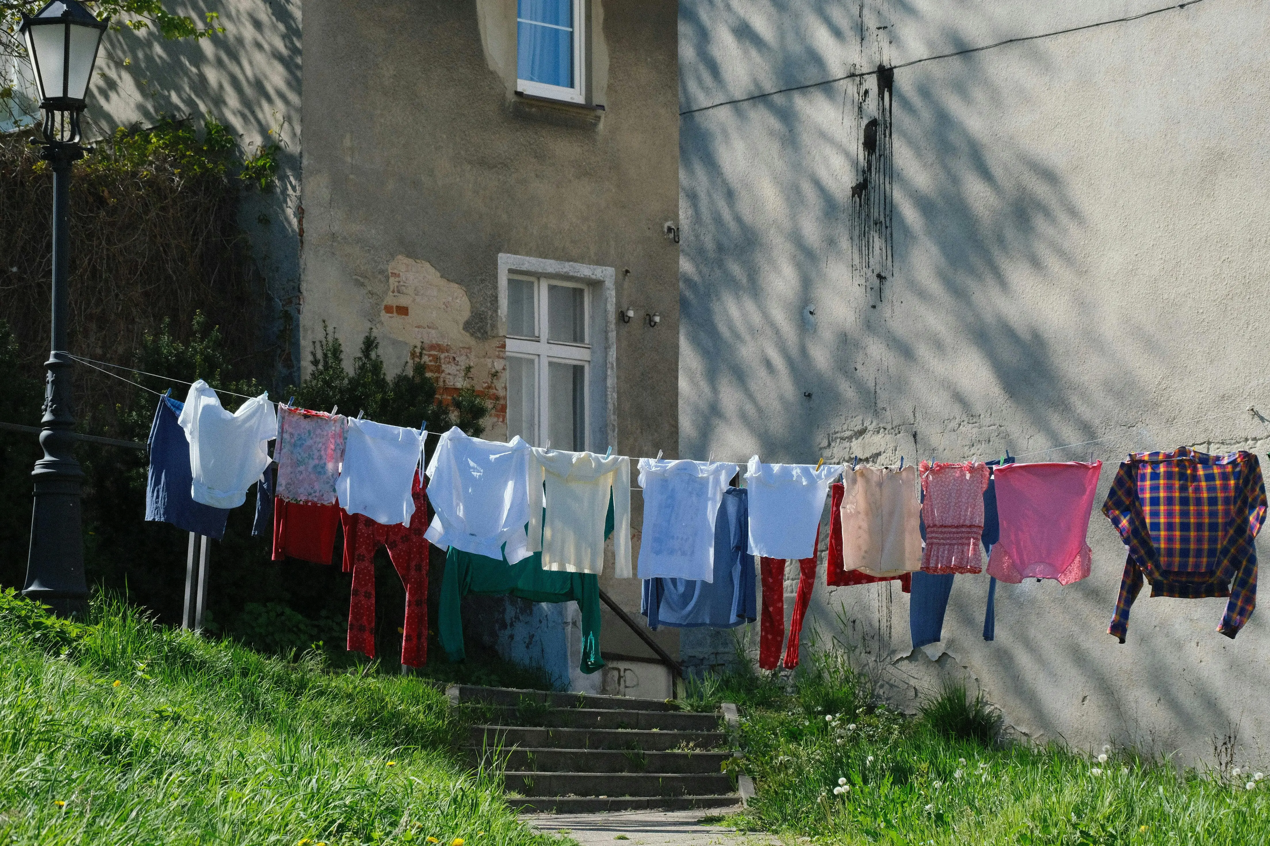 how to get urine smell out of clothes Vibrant clothes hanging on a line outside a rustic building on a sunny day.