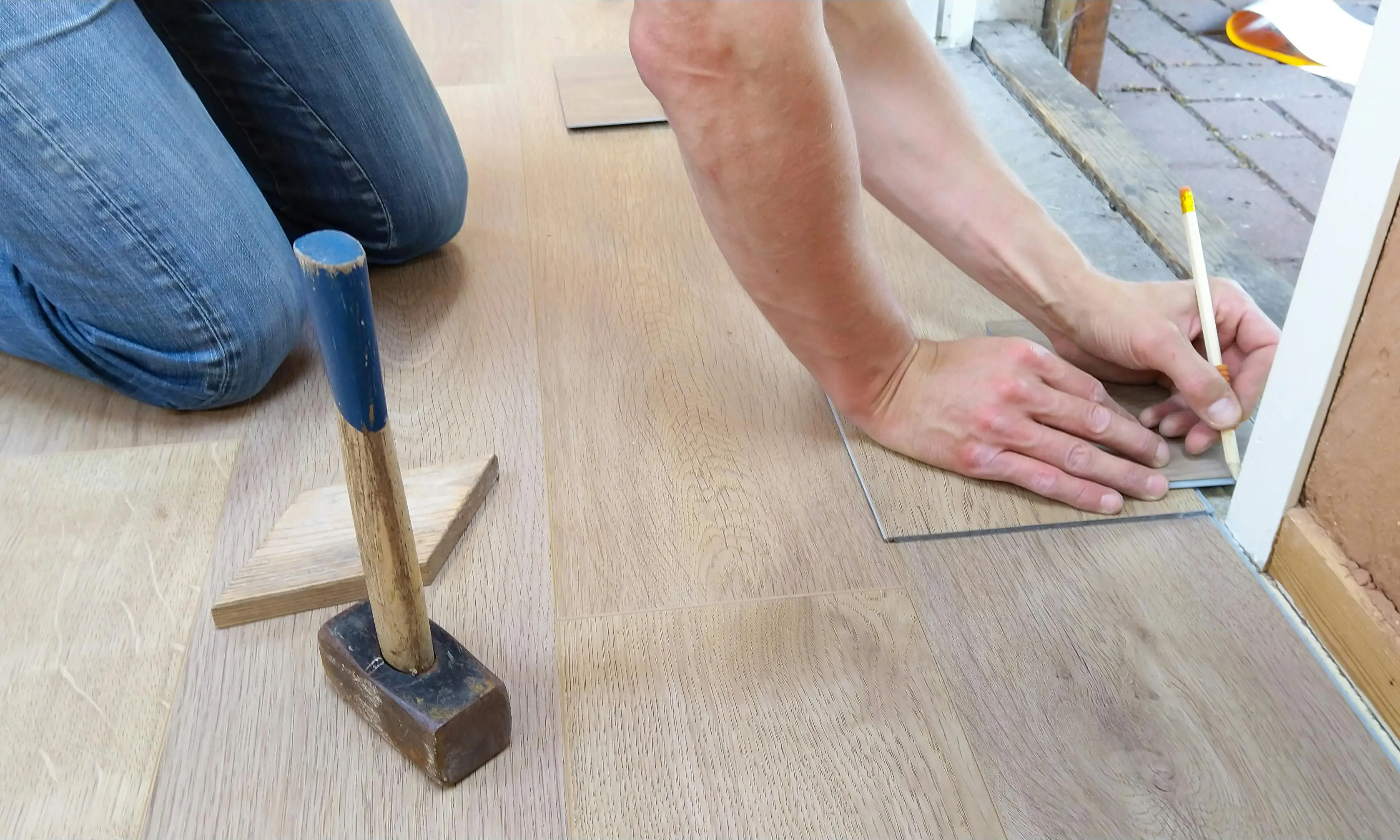 how to cut laminate flooring A craftsman carefully measures and marks wooden floor panels for precise installation.