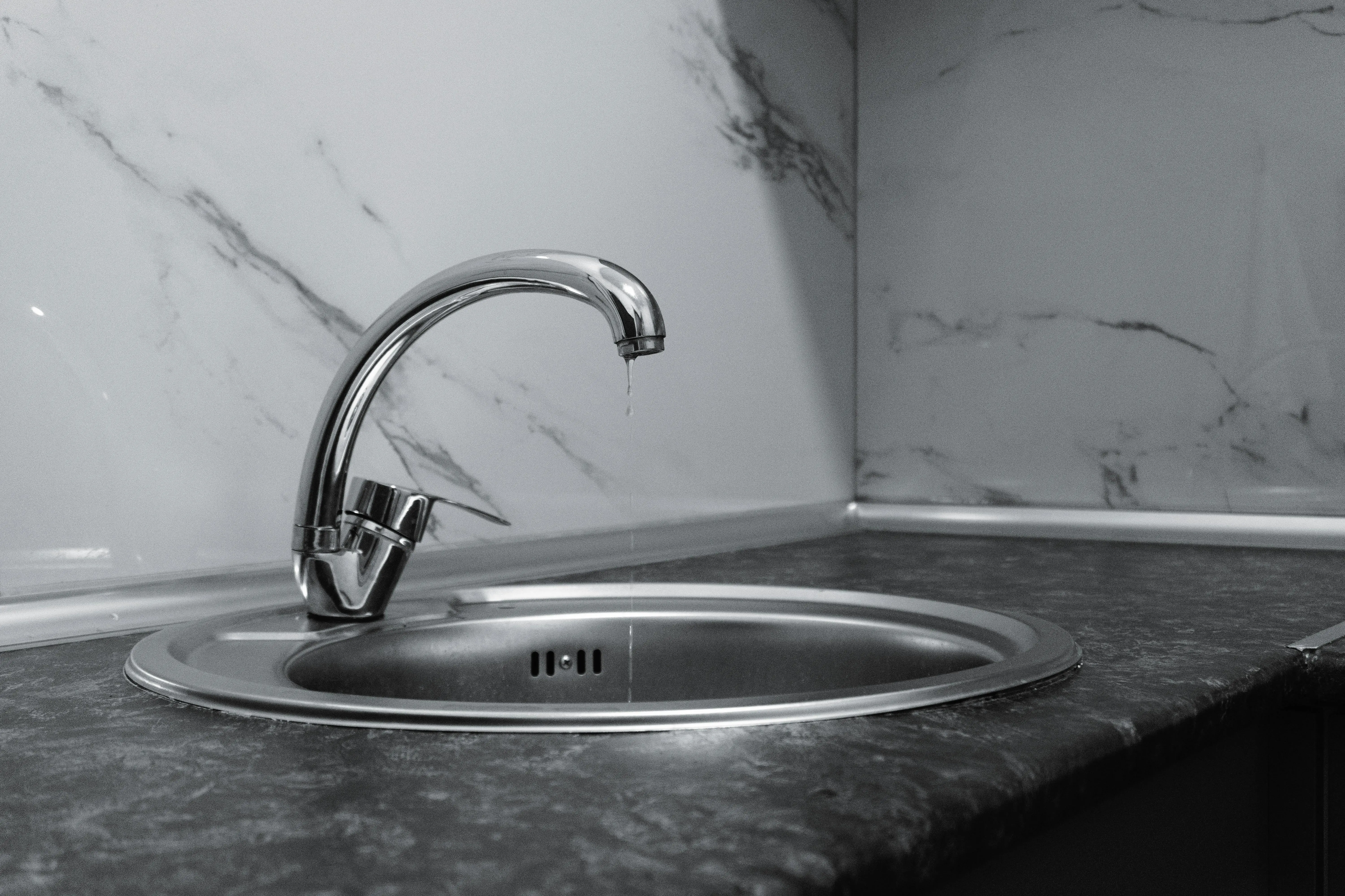cracked sink repair A clean and modern kitchen sink with a chrome faucet, highlighting minimalist design and water conservation.
