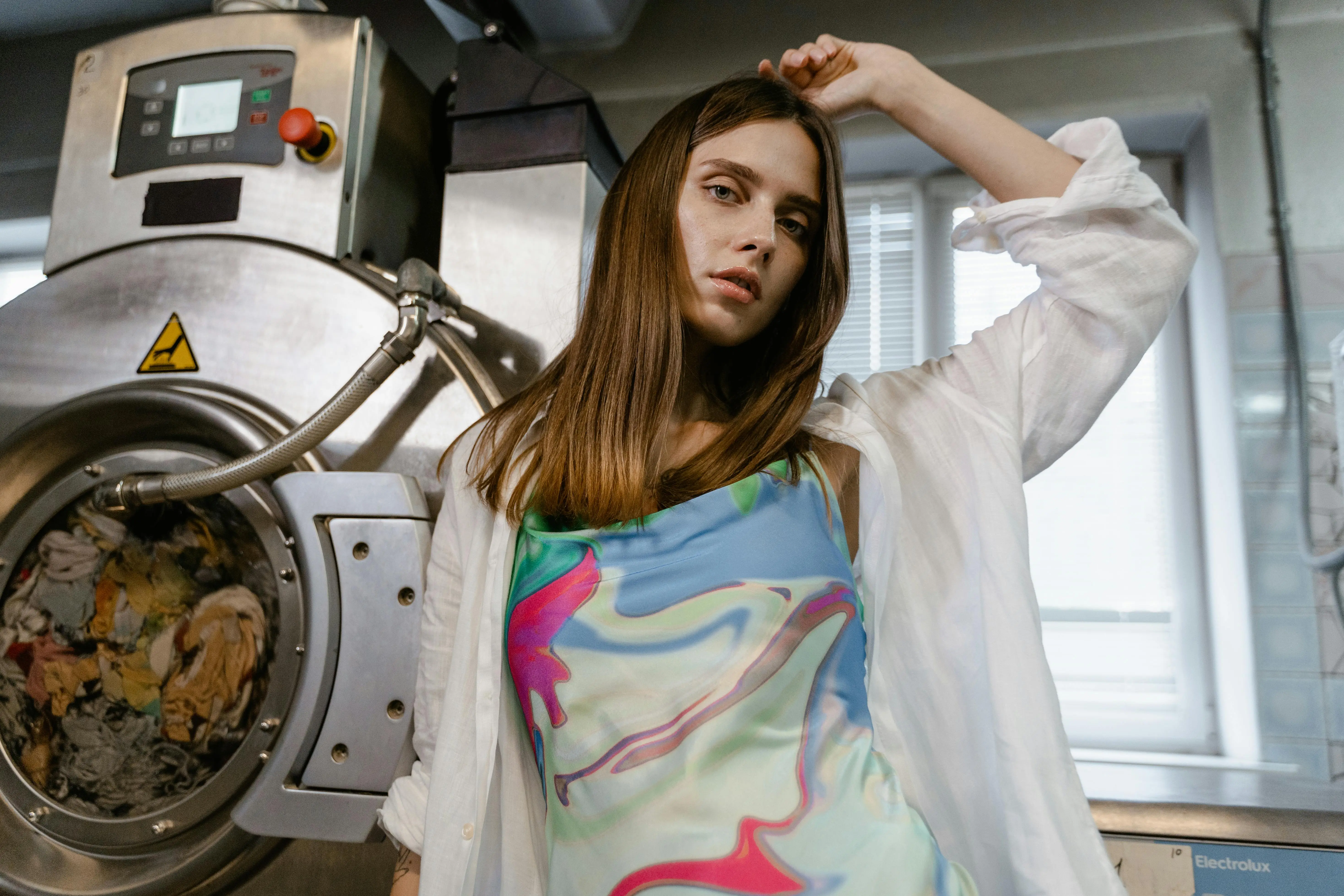 how to get tree sap out of clothes Stylish woman posing next to a large industrial washing machine indoors.