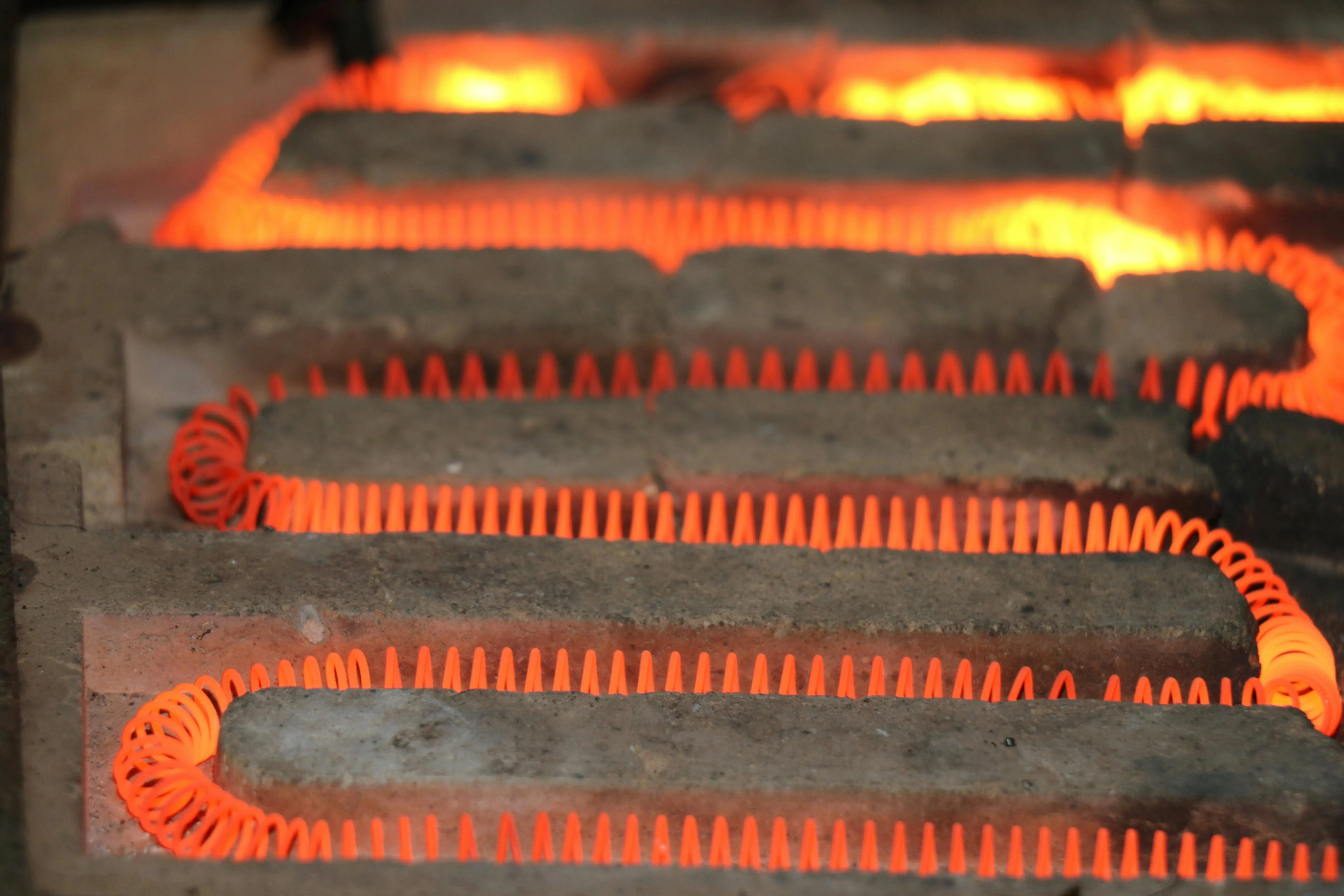 how to clean evaporator coil Detailed view of a glowing electric heating element with a coiled structure emitting heat.