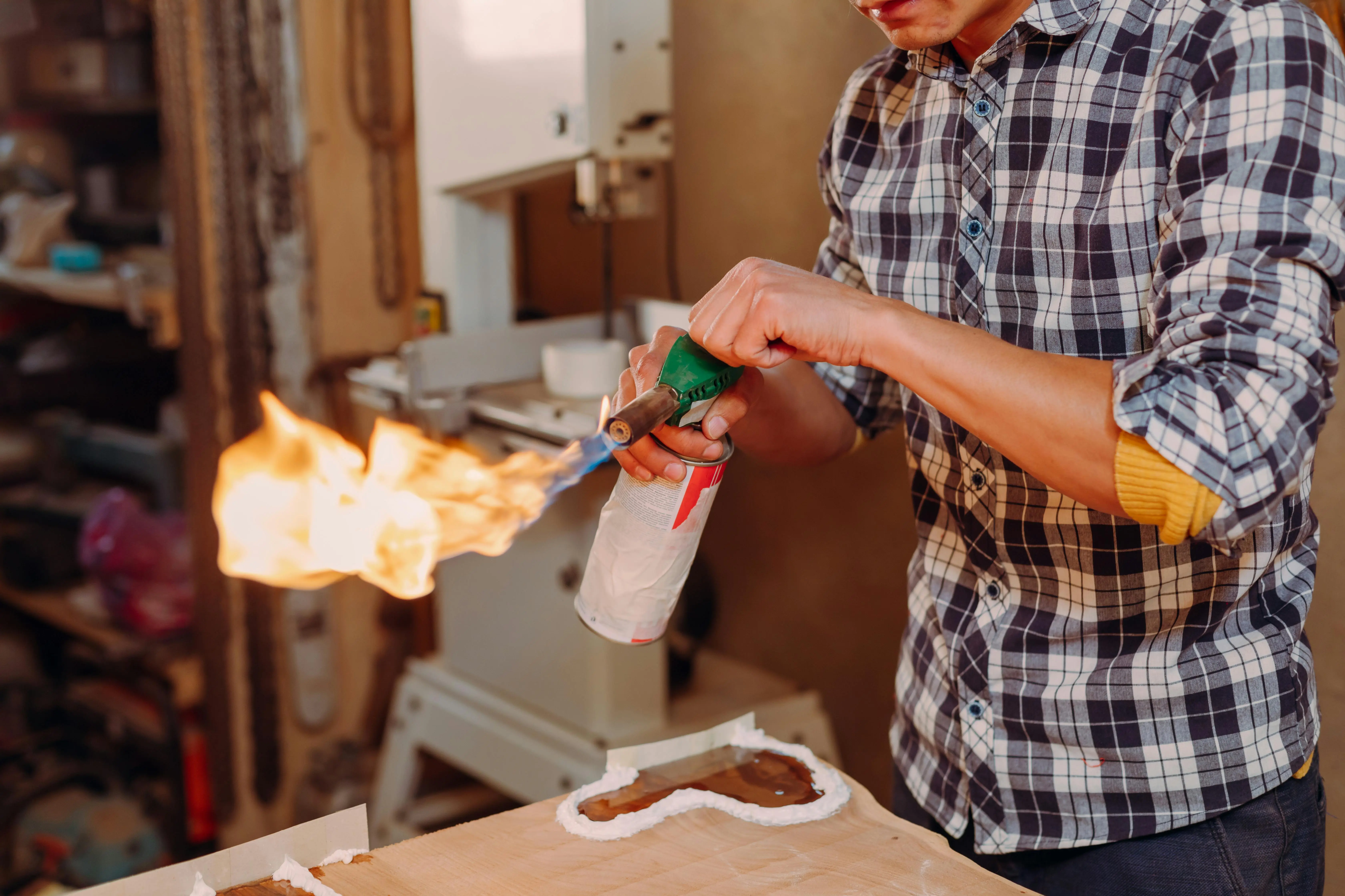 diy garage floor coating Closeup of an artisan using a blowtorch to work on epoxy resin in a workshop.