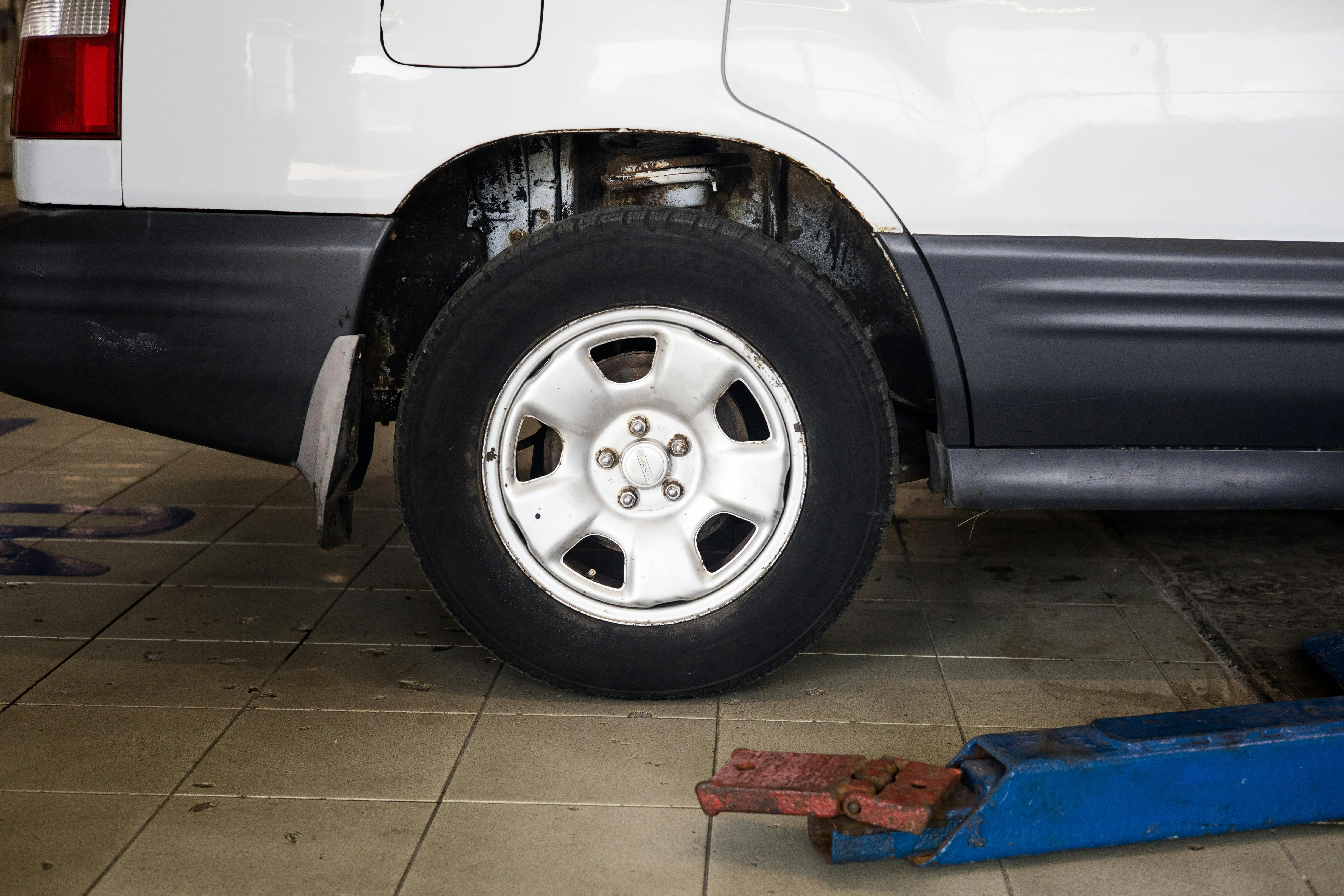 diy garage floor coating Detailed view of a car wheel in an auto repair shop setting with a hydraulic jack.