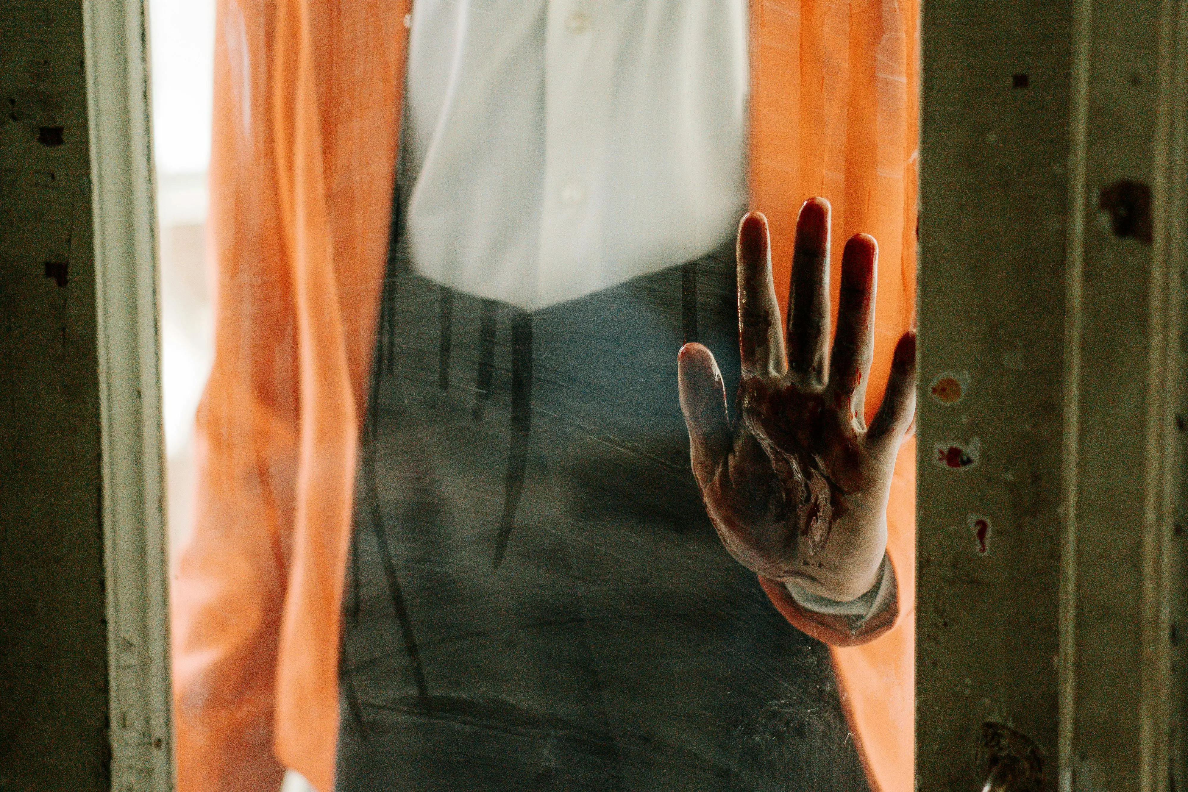 how to get period blood out of clothes A spooky handprint left on a dusty glass door, conveying a sense of horror.