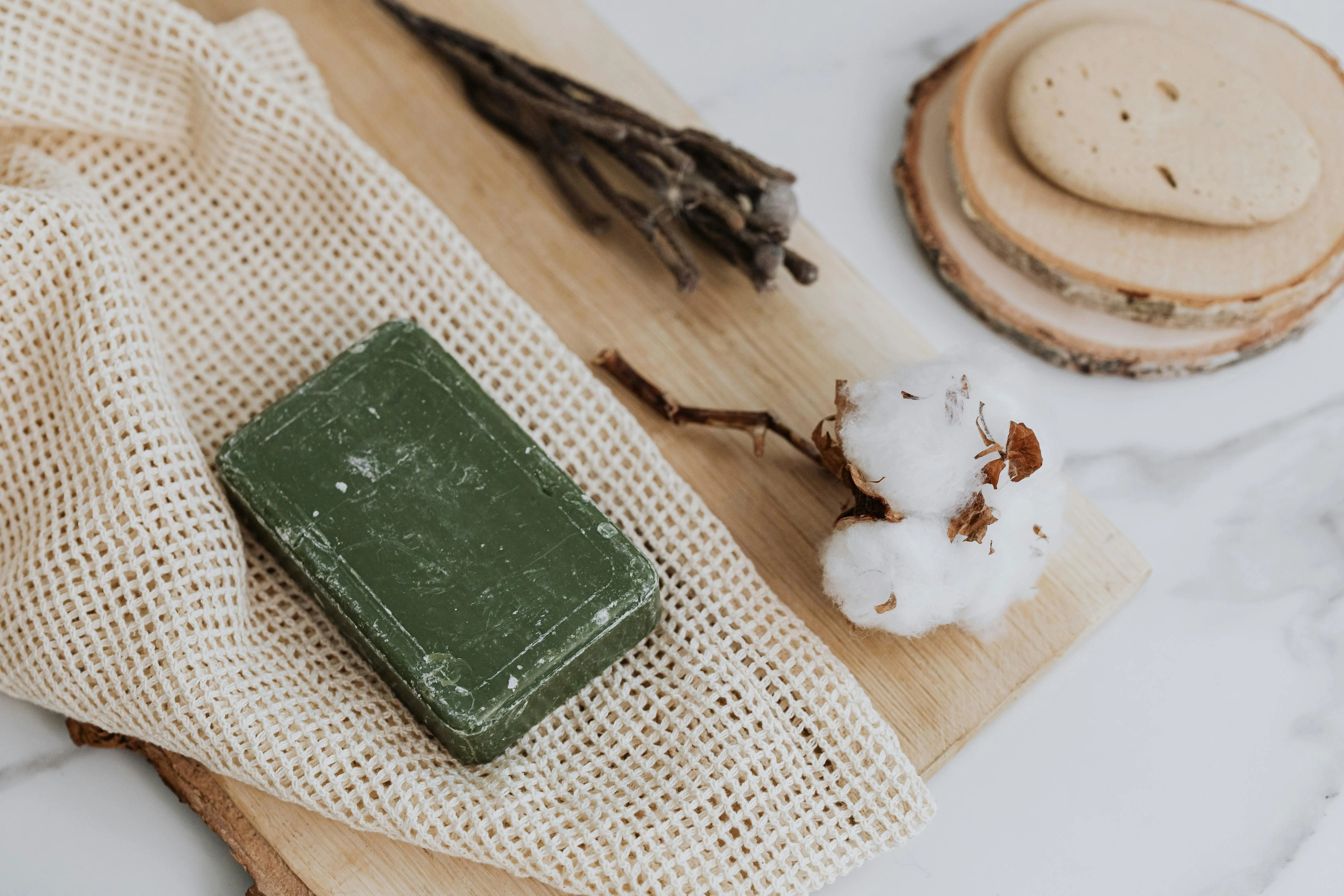 clean with green Natural green soap with cotton and loofah on wooden board promoting zero waste lifestyle.
