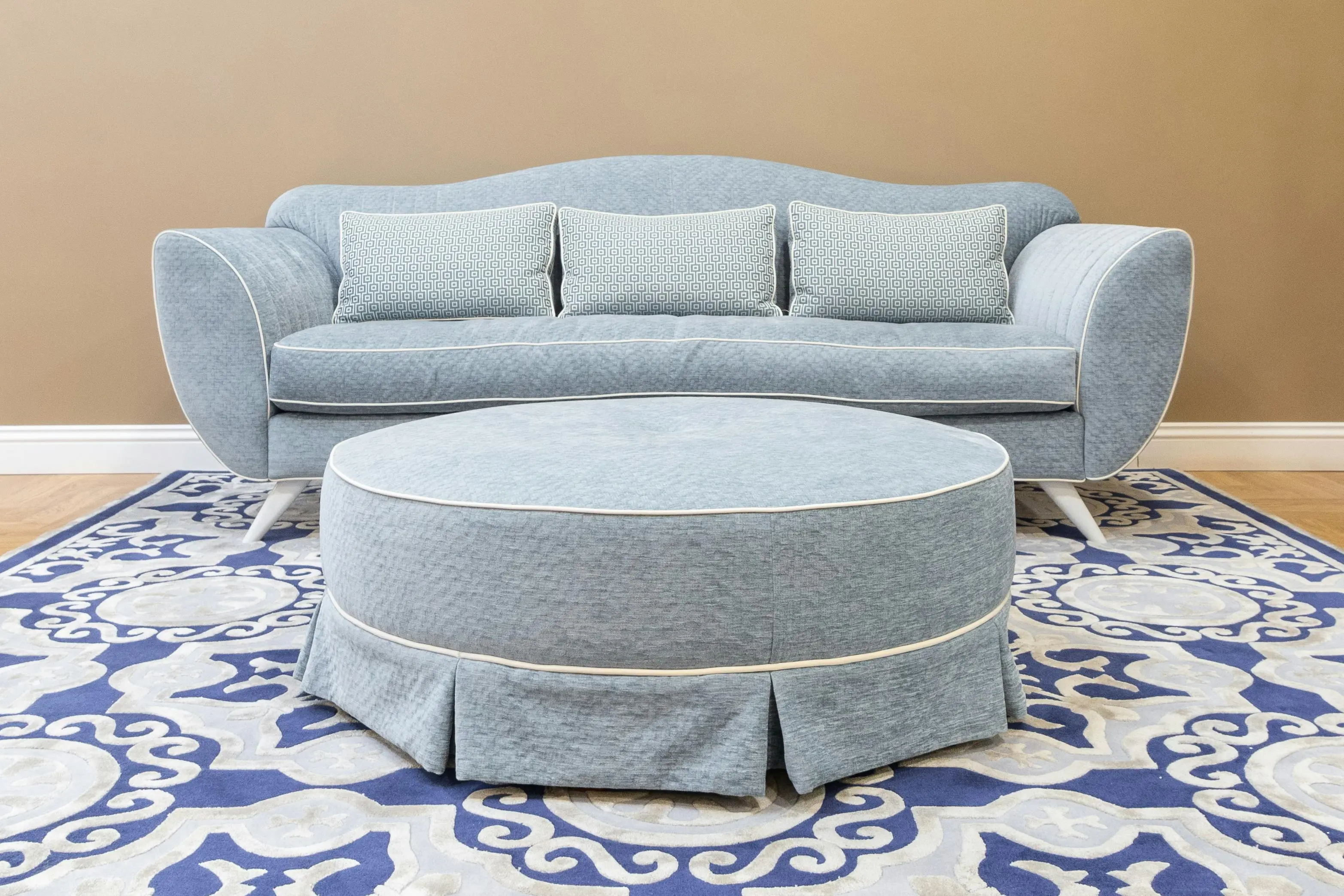 what might be placed in a secondary furniture A stylish blue sofa with matching ottoman and decorative rug in a modern living room setting.