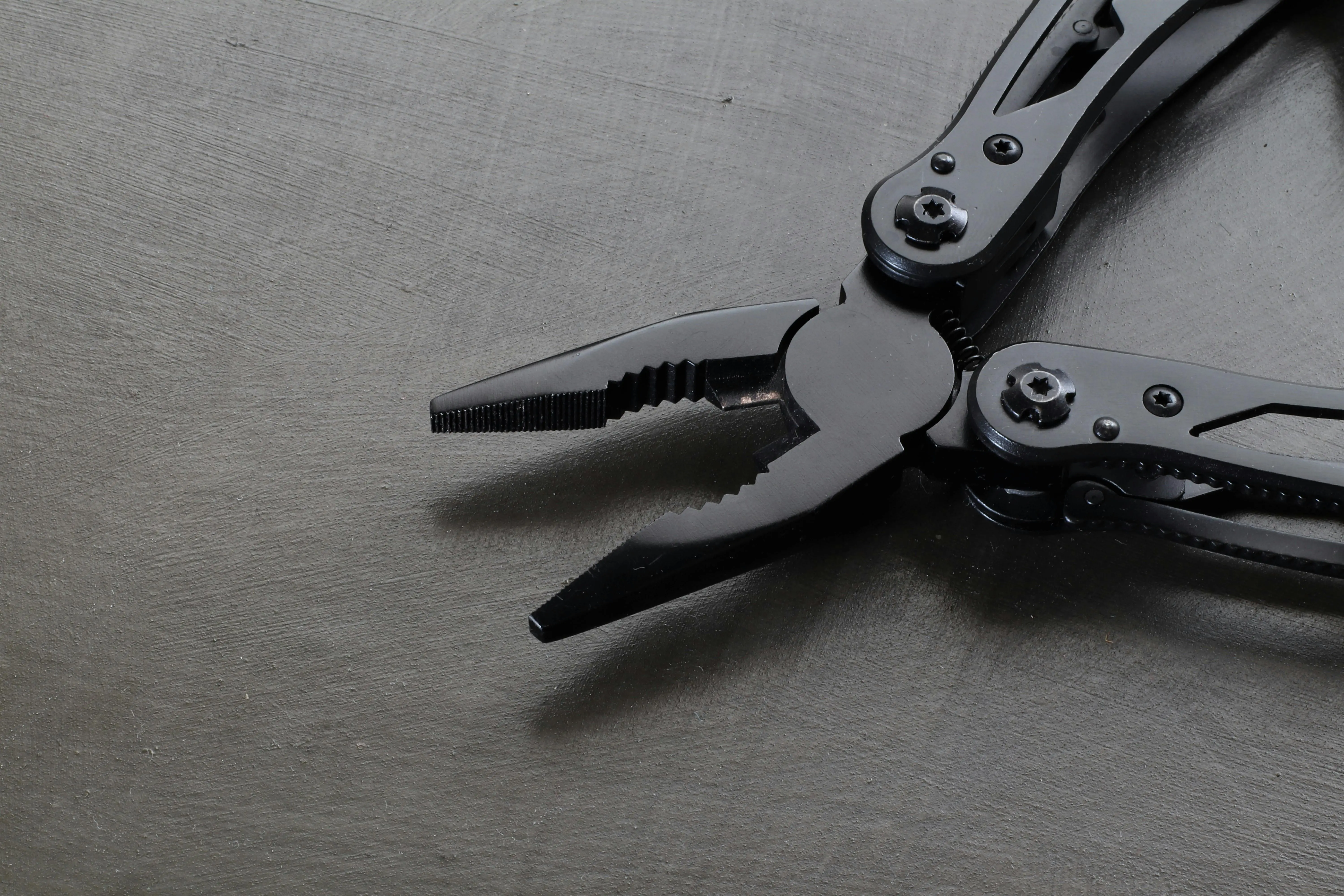 black cabinet knobs Black metal pliers on a dark surface, emphasizing industrial precision and durability.