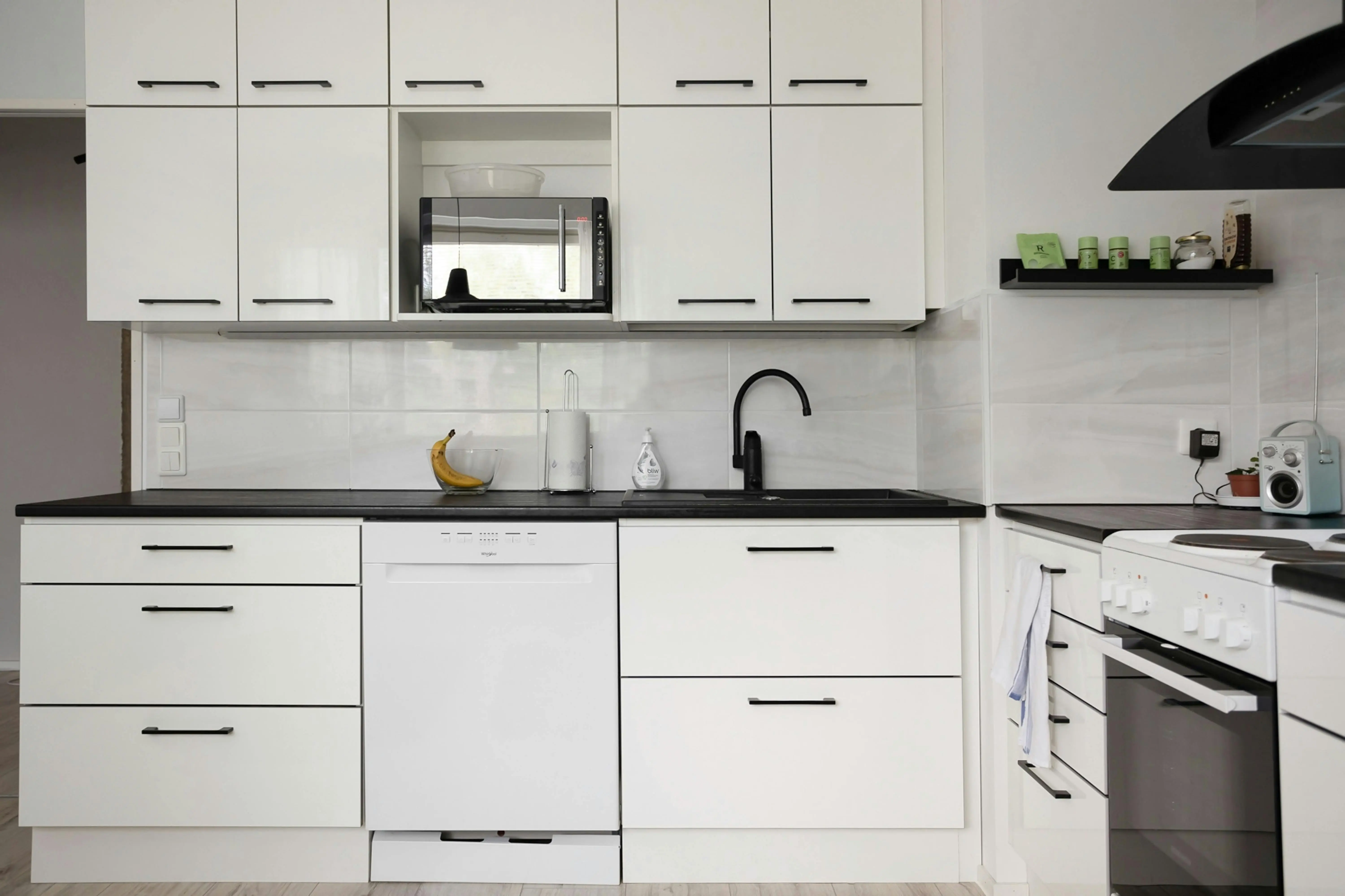 black cabinet knobs Sleek and modern white kitchen with appliances, showcasing contemporary interior design.
