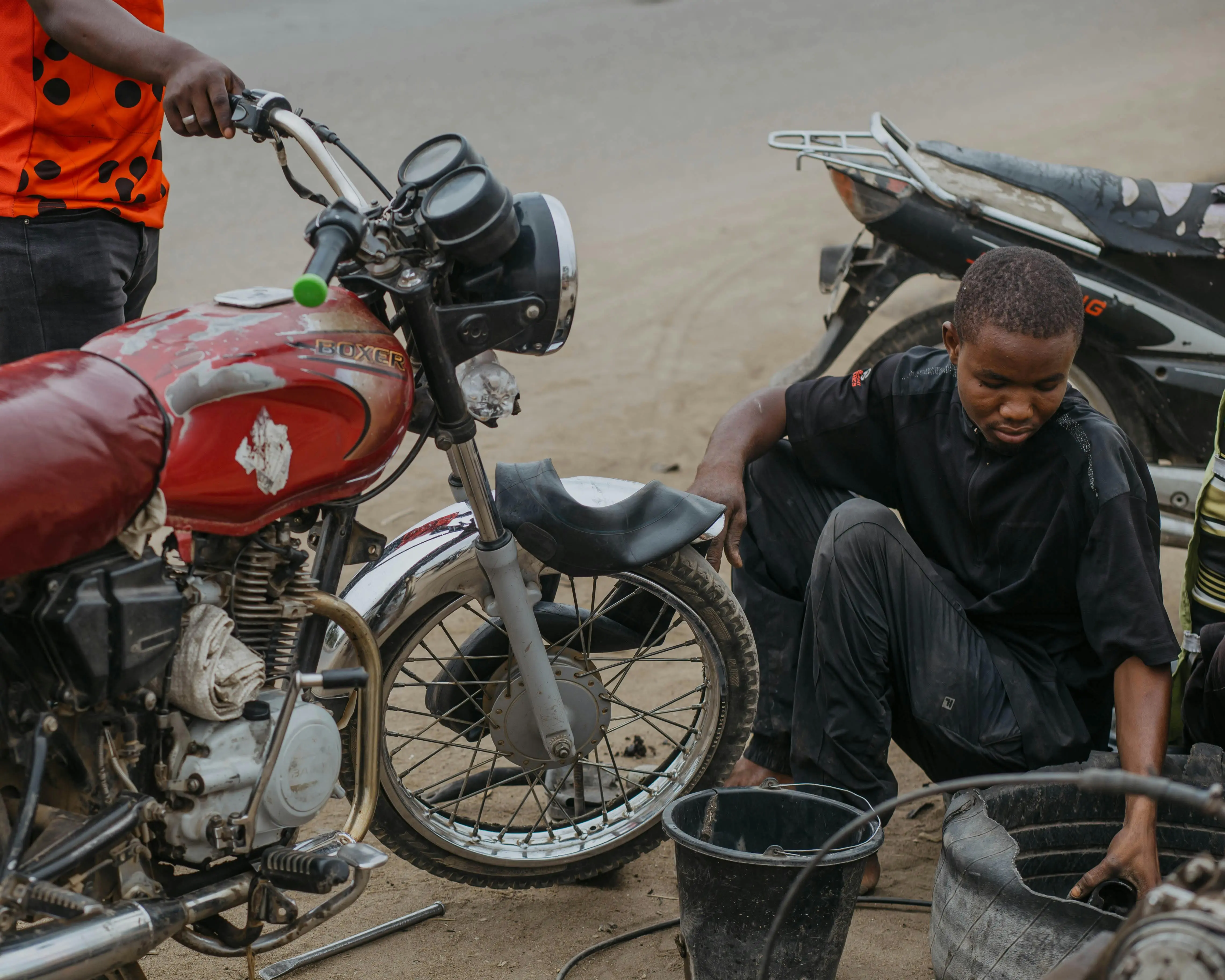 how to get motor oil out of clothes A young mechanic in black repairs a motorcycle on a dusty street.