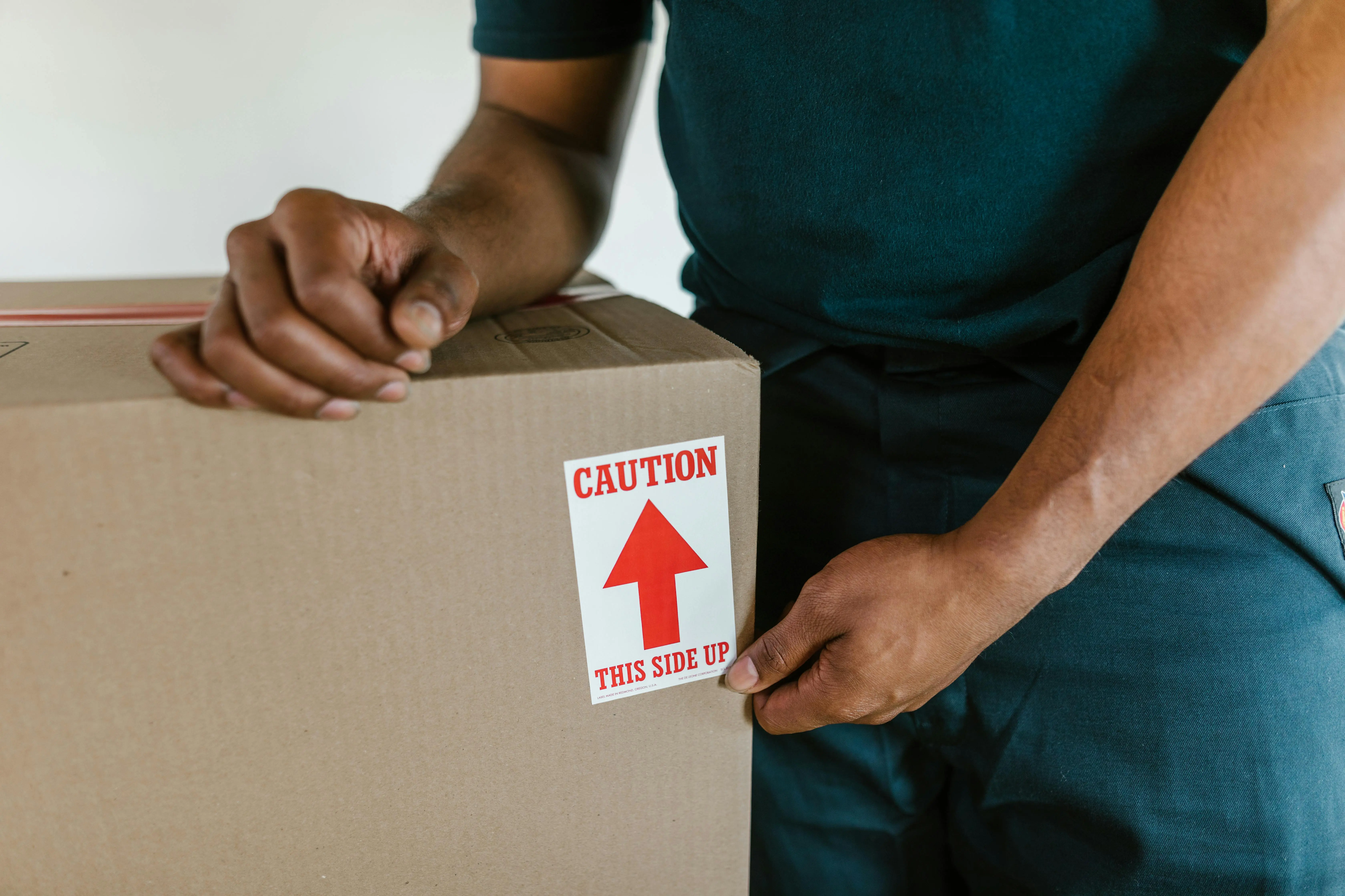 how much does a washing machine weigh A person handling a moving box with a 'caution this side up' label indoors.