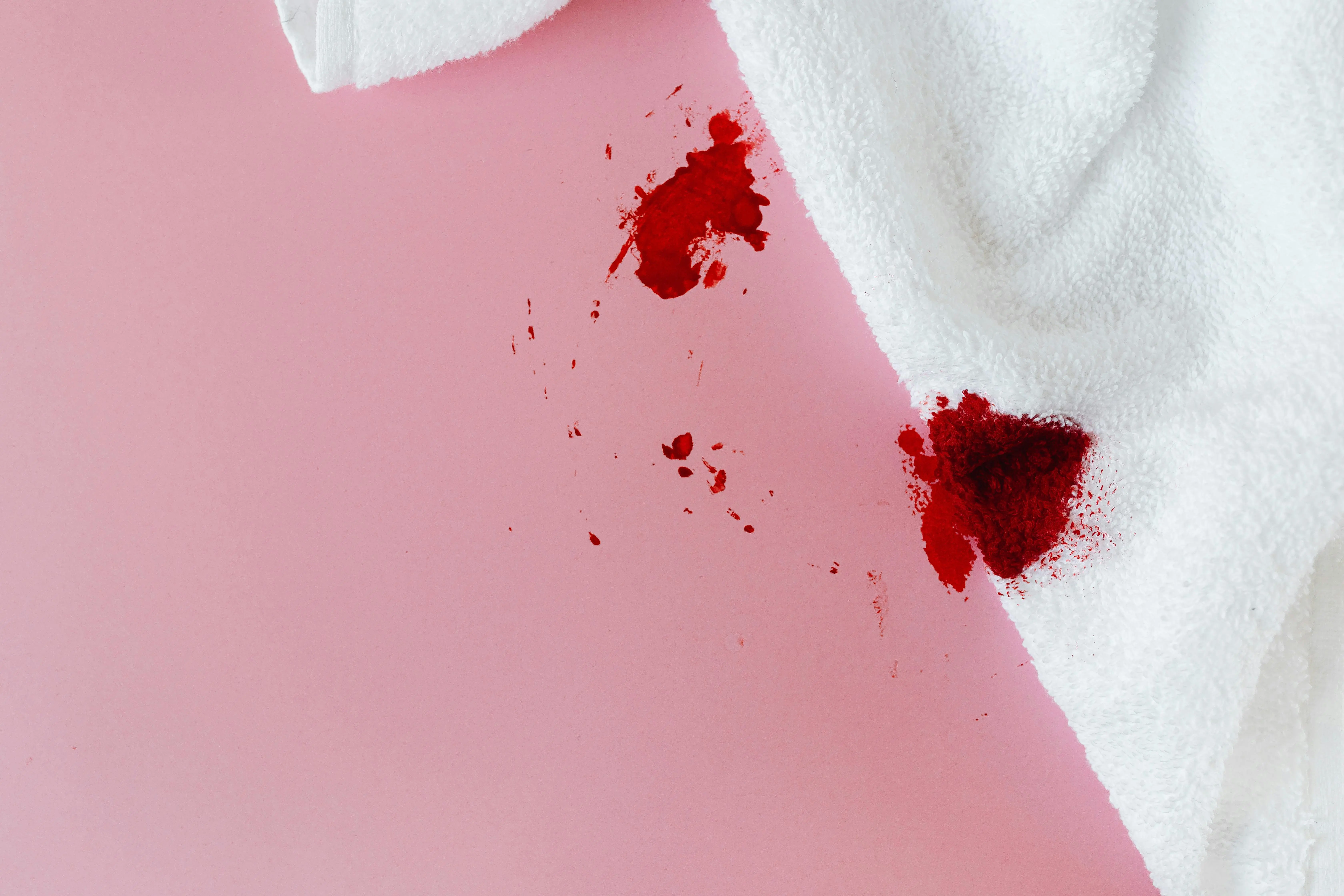 how to get motor oil out of clothes White towel with red blood stains on pink surface, showing menstrual concept.