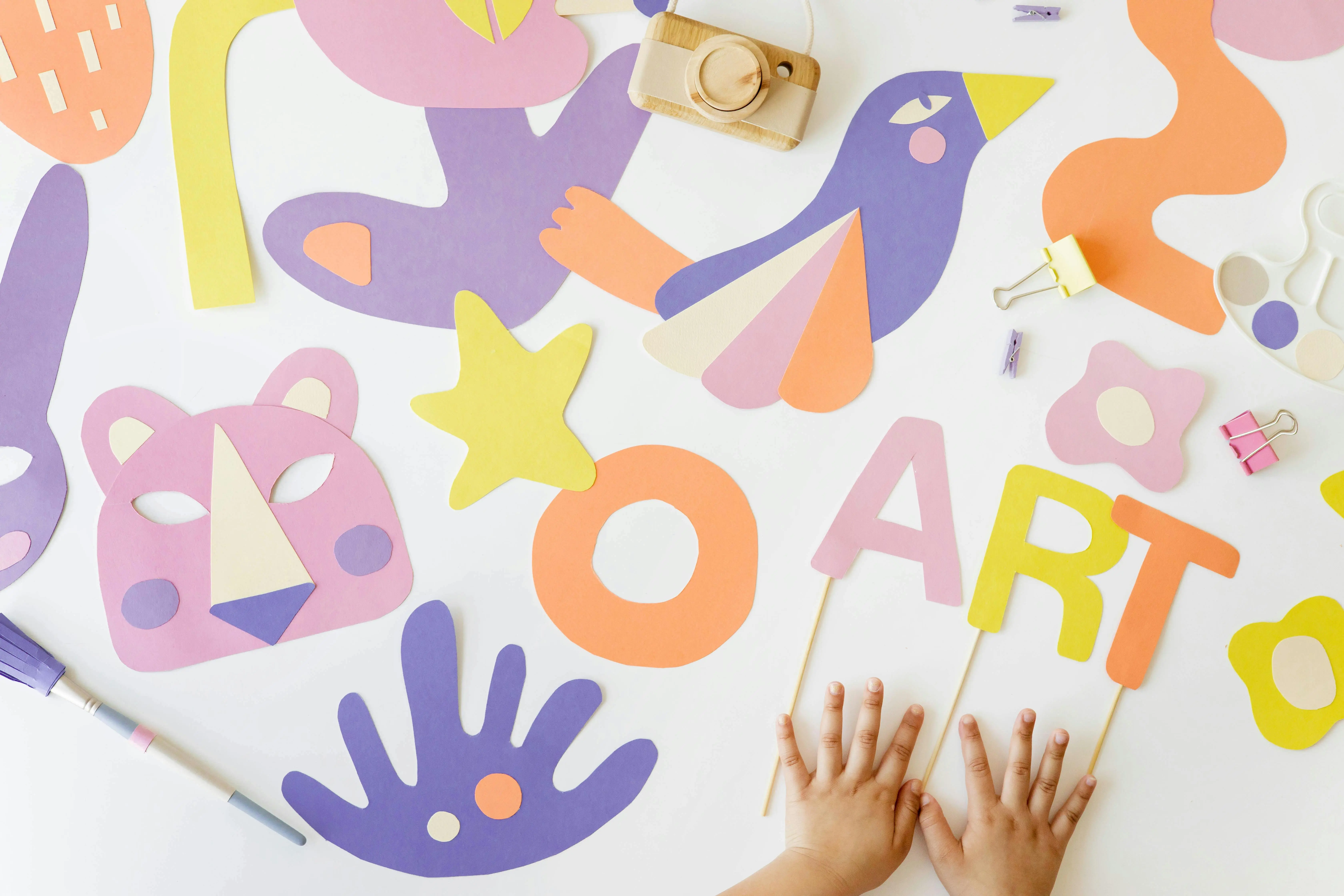 crafts for pre k Creative art and craft layout with colorful paper cutouts and child's hands, viewed from above.
