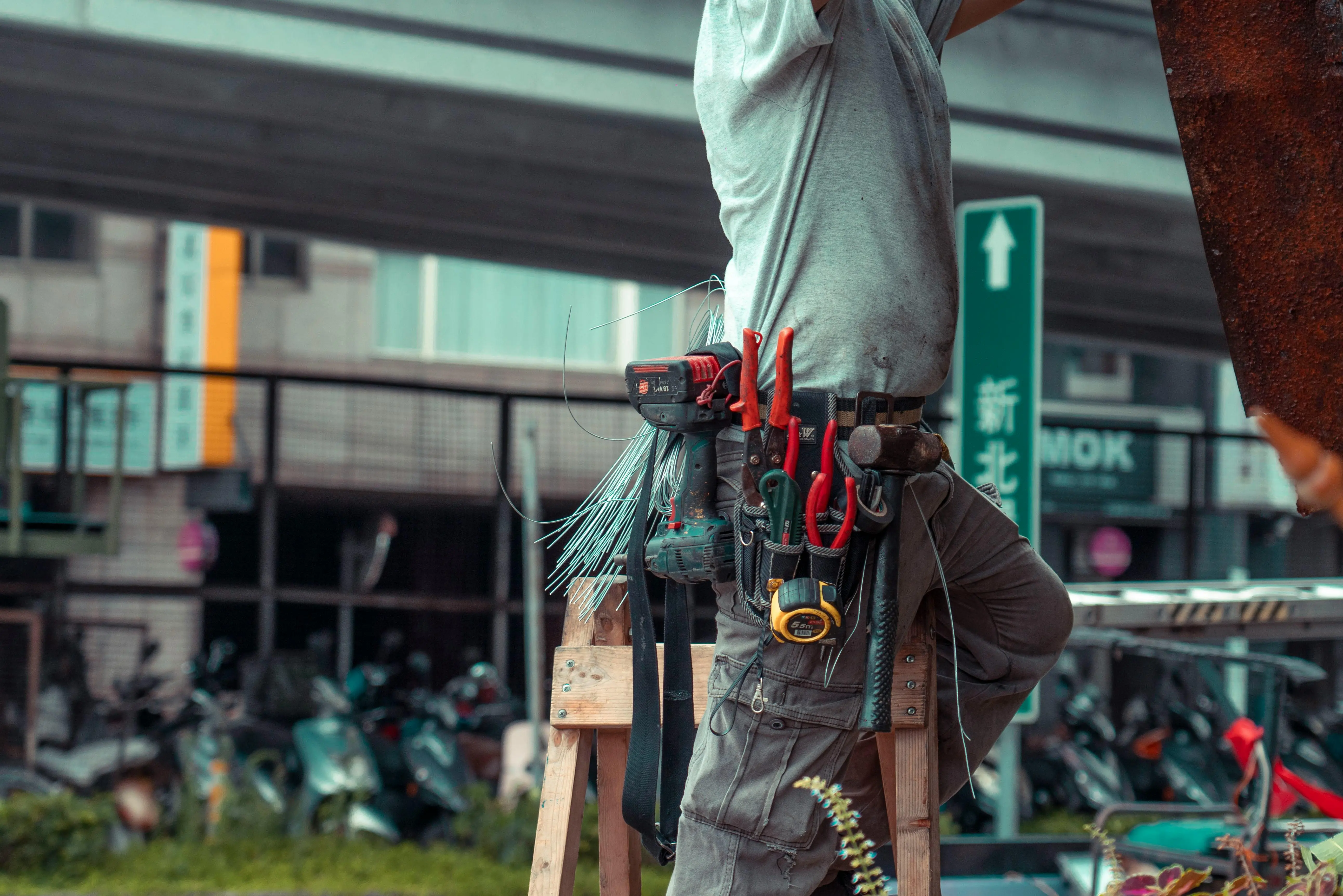 cracked sink repair Handyman standing on a ladder with tool belt, repairing outdoors with visible tools.