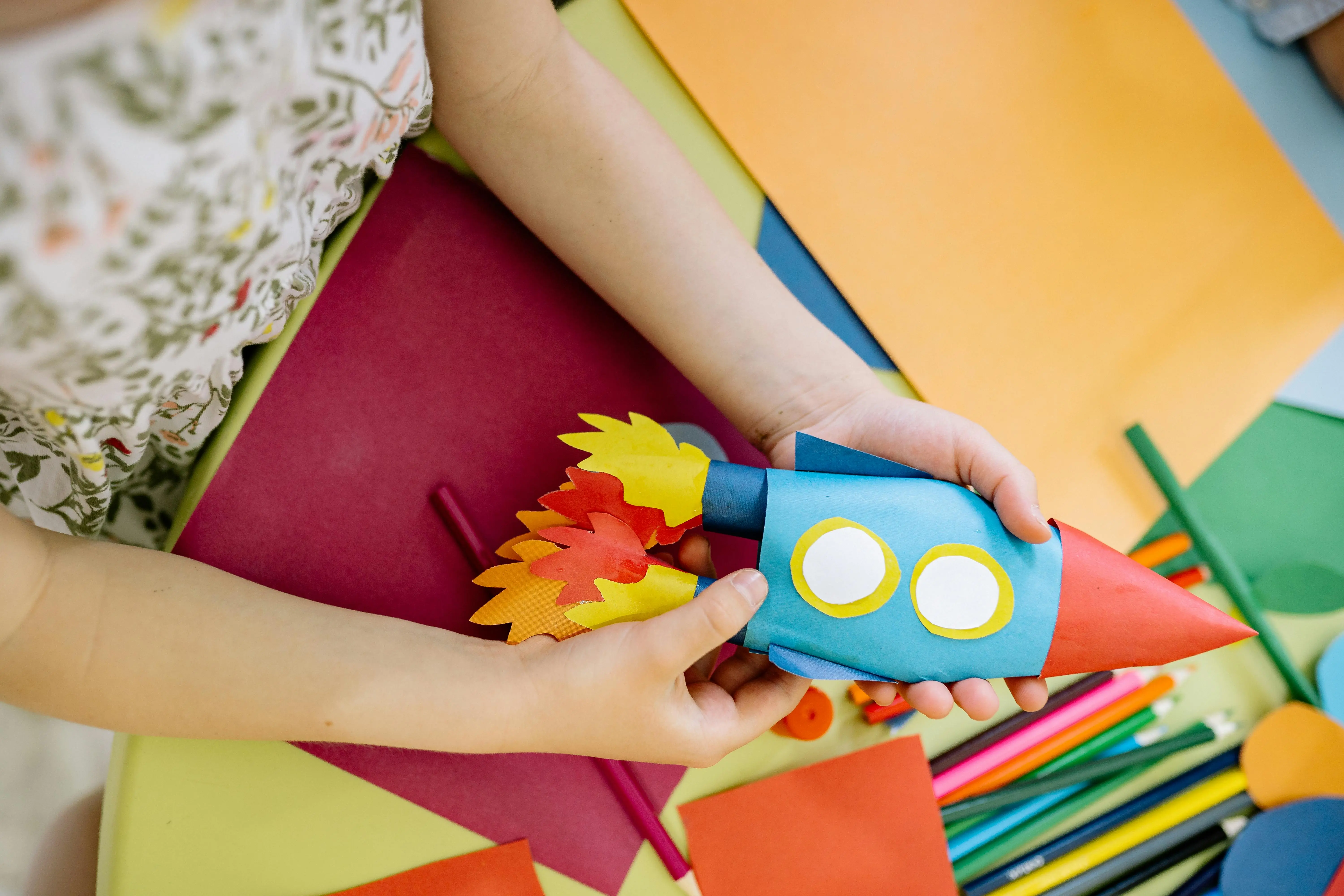 crafts for pre k A child builds a vibrant paper rocket during an arts and crafts session, fostering creativity.